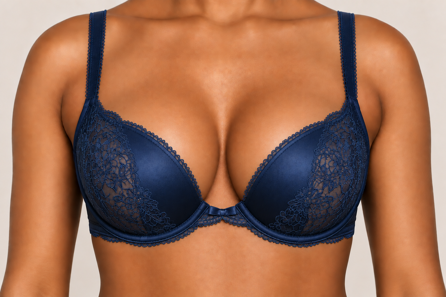 Close-up of a woman wearing a navy blue lace bra with floral embroidery and satin bow detail.