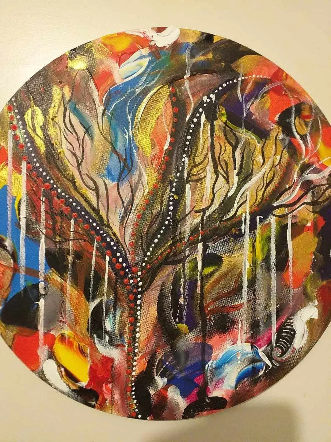 Abstract painting with vibrant colors, black lines, and dotted patterns on circular canvas.