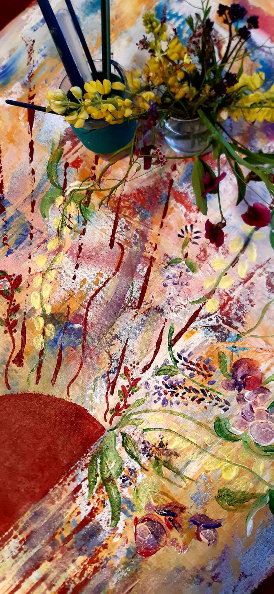 Close-up of a floral arrangement in glass vases on an abstract, colorful tablecloth with swirl and line patterns.
