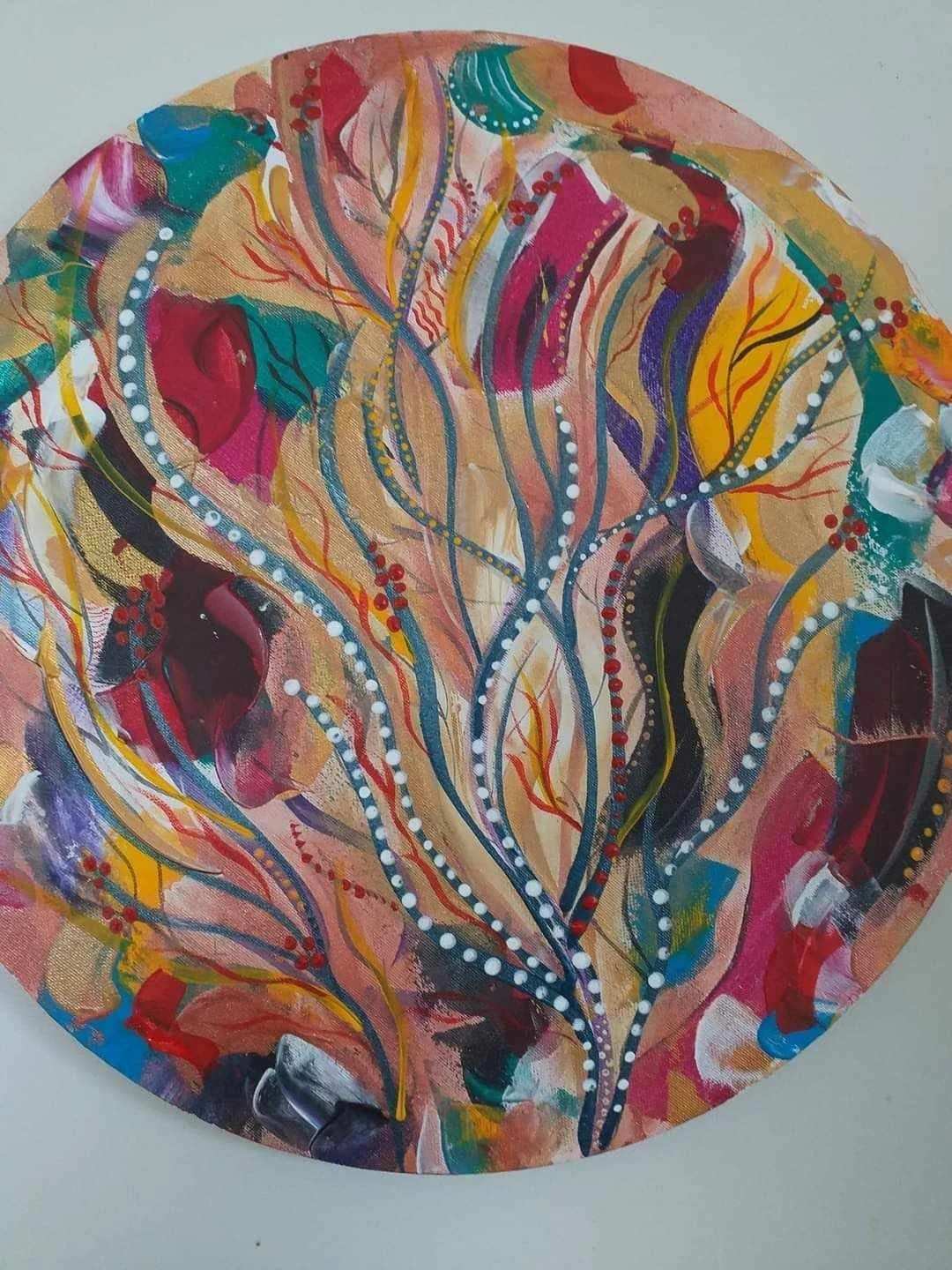 Abstract colorful painting with flowing lines, dots, and leaf shapes on circular canvas.