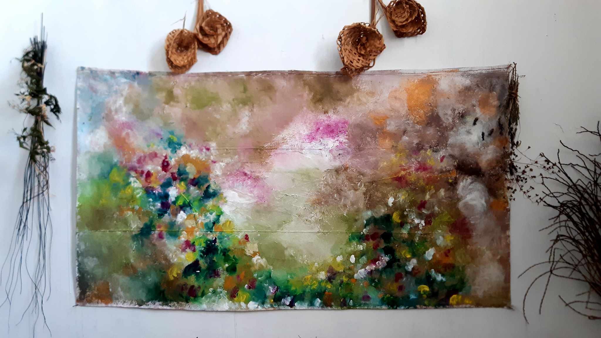 Abstract colorful painting with splashes of pink, green, yellow, white, and brown hues, surrounded by dry botanical arrangements on white background.