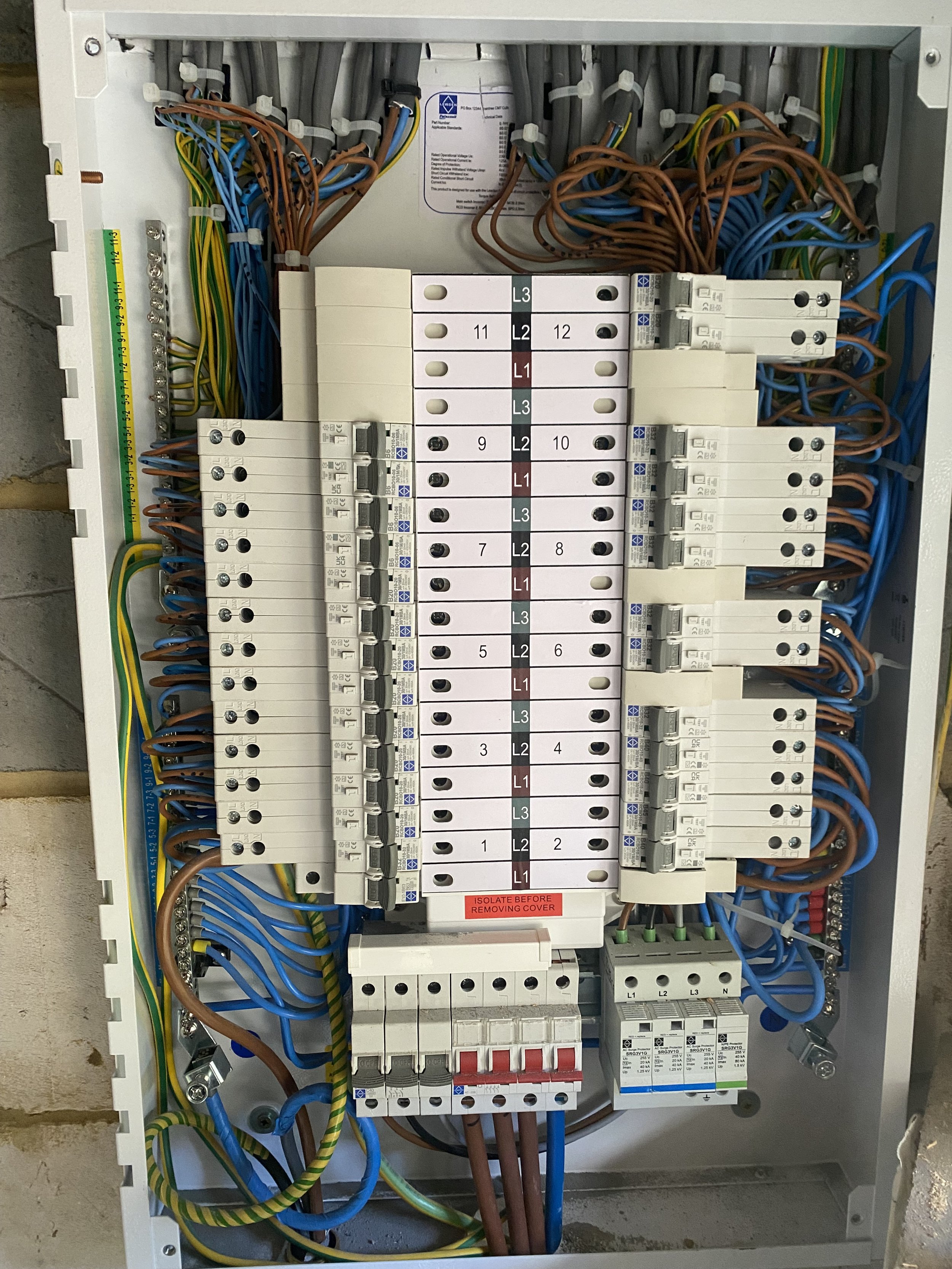 An electrical breaker panel with various colored wires, switches, and labels inside a metal box.