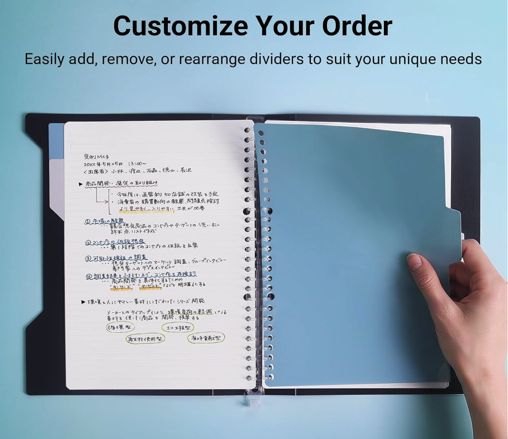 Open binder with customizable dividers and handwritten notes on the left page, blue divider tab on right side, hand holding the right page, light blue background.