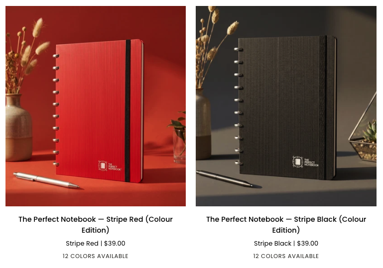 A side-by-side display of two notebooks: one with a red, striped cover and one with a black, striped cover. Each is accompanied by a silver pen and a vase with dried flowers, with a warm background behind the red notebook and a cooler background behind the black notebook. The notebooks are labeled as 'The Perfect Notebook' in different colors and are priced at $39.00, with 12 colors available.