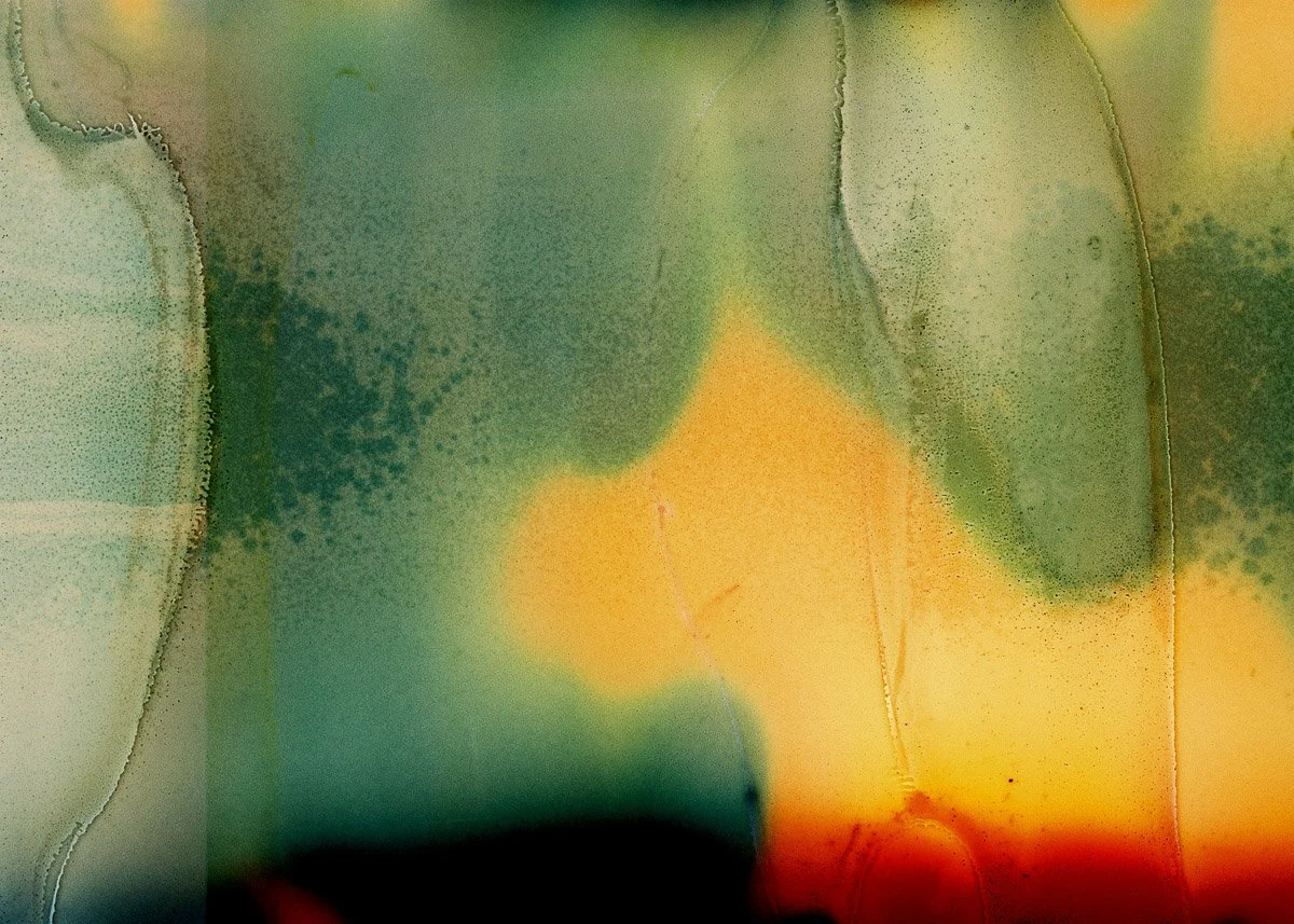 Abstract watercolor painting with green, yellow, and orange hues blending and flowing together, with visible textures and soft edges.