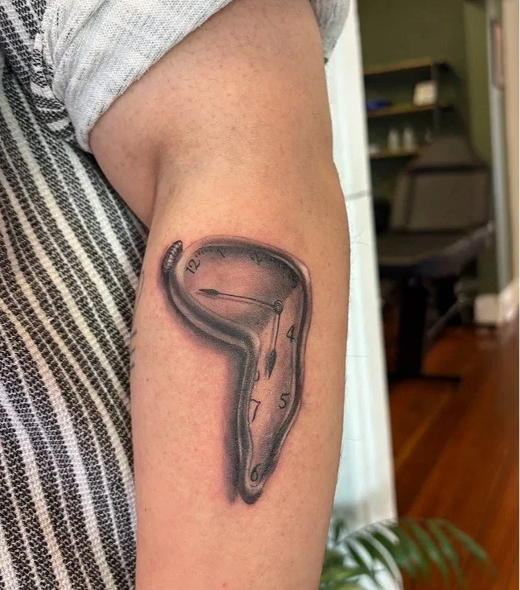 A tattoo of a melting clock on a person's upper arm.