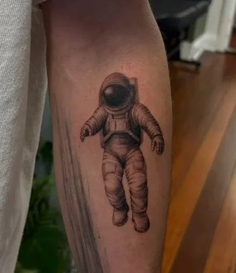 Tattoo of an astronaut in a space suit on person's arm.