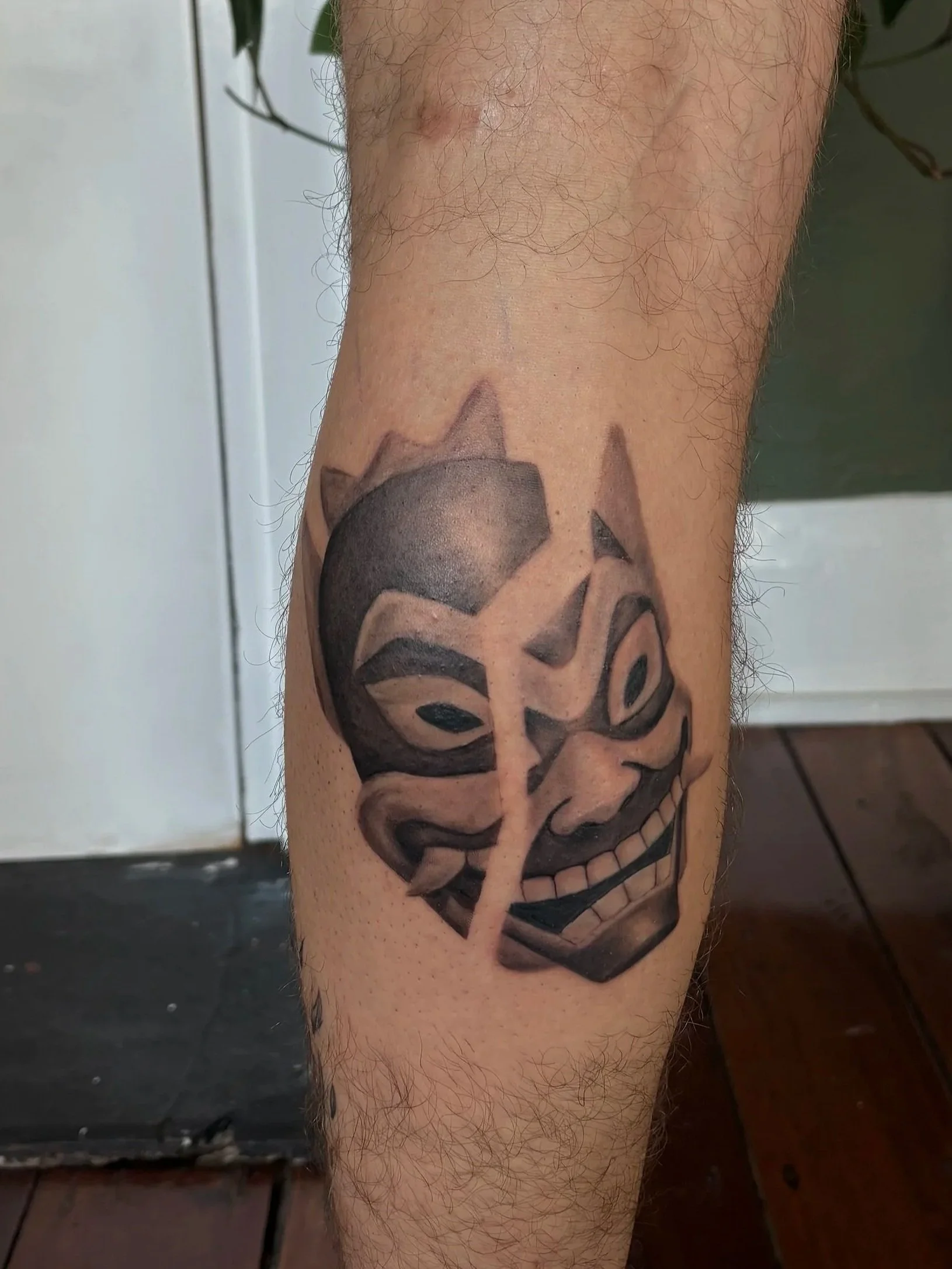 Close-up of a person's lower leg with hair and a tattoo of a stylized skull and flowers.