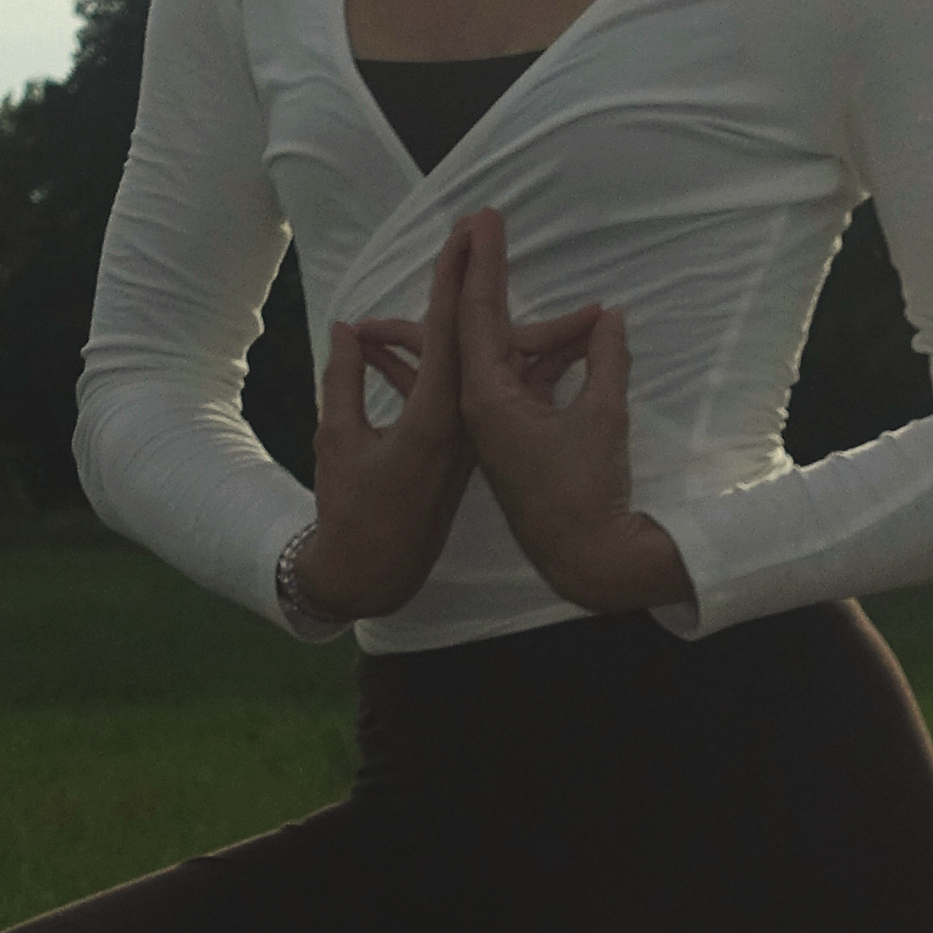 Person praktiziert Yoga im Freien, Hände in der Gebetsposition, während der Abend oder frühen Morgen kommt.