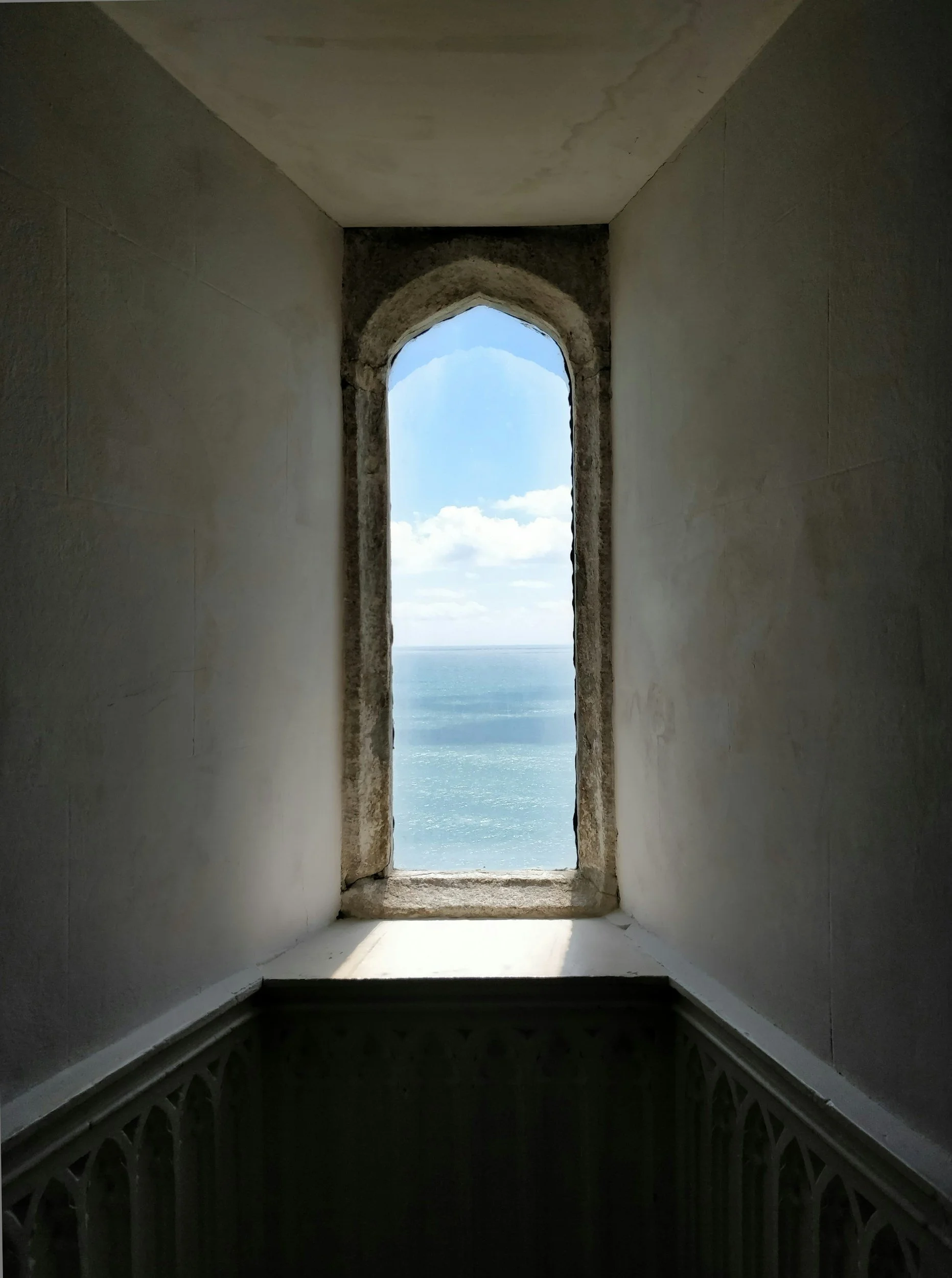 Stone archway with a view of the sea & sky.