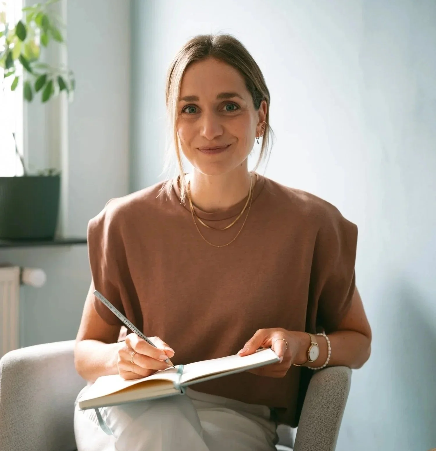 M.Sc. Psych. Hanna Breit, die in einem Raum mit natürlichem Licht sitzt, ein Notizbuch hält und schreibt.