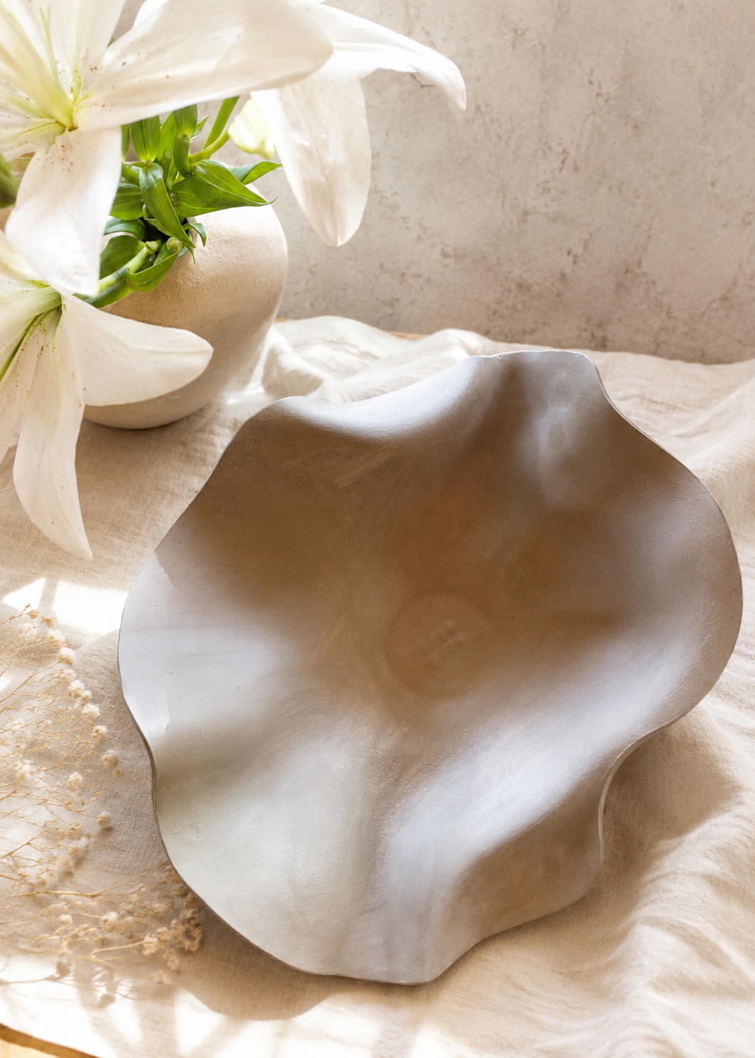 Eine organisch geformte Belly Bowl, welche direkt am Bauch entstanden ist. Natürlicher, leichter, heller Hintergrund mit weißen Blumen.