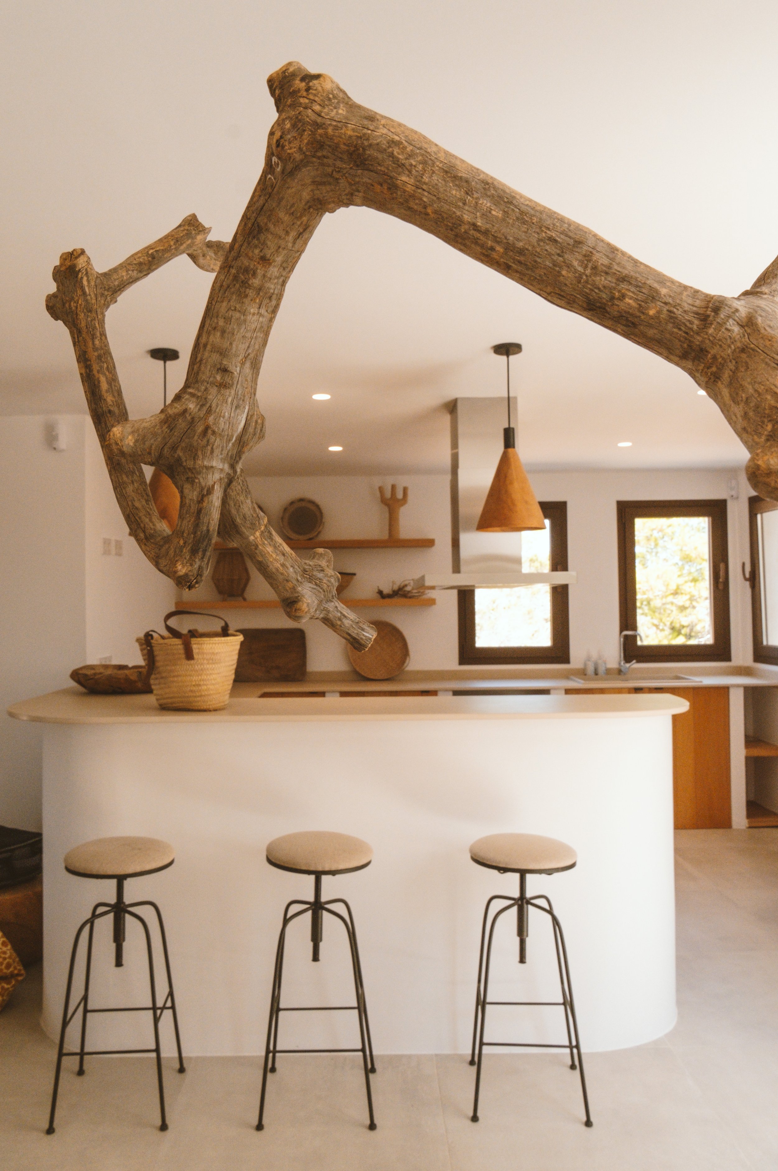 Interiores modernos de cocina con barra y asientos, decorada con madera rústica en la estructura de la barra y lámpara de tono marrón.