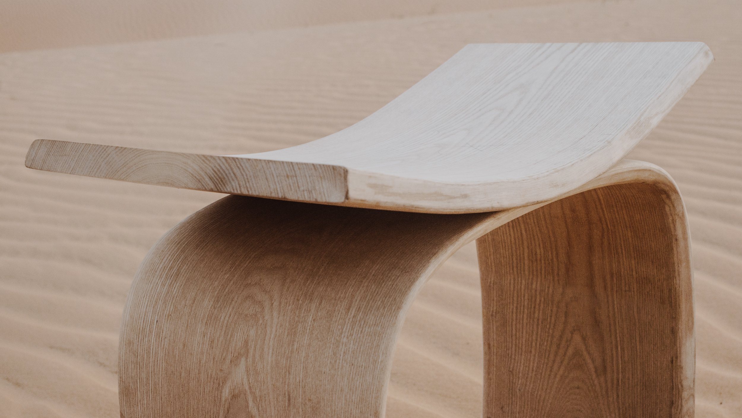 Una imagen de varias sillas de madera con diseño moderno y curvo, apiladas unas sobre otras