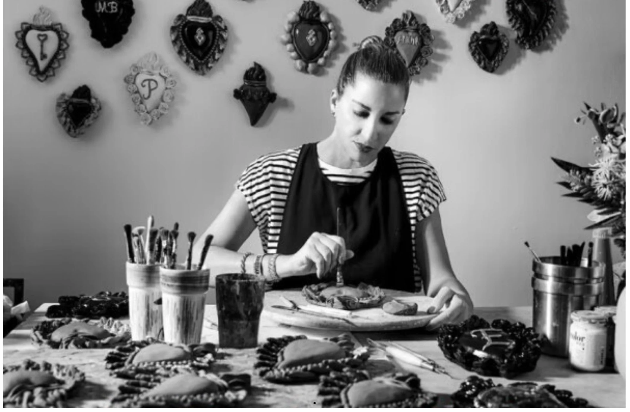 Une femme travaille de l'argile dans un atelier, avec des décorations de cœurs en arrière-plan.