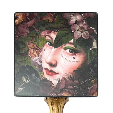 Miroir décoratif avec visage de femme entouré de fleurs et d'insectes, avec un pied doré.