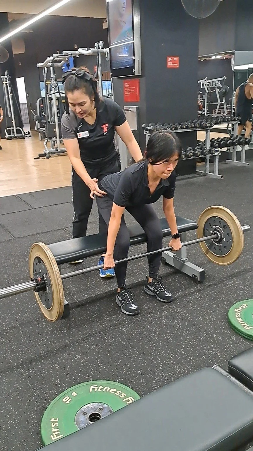 Client performing a barbell deadlift during a personal training session with Vera Yazid at Fitness First Market St, Sydney.