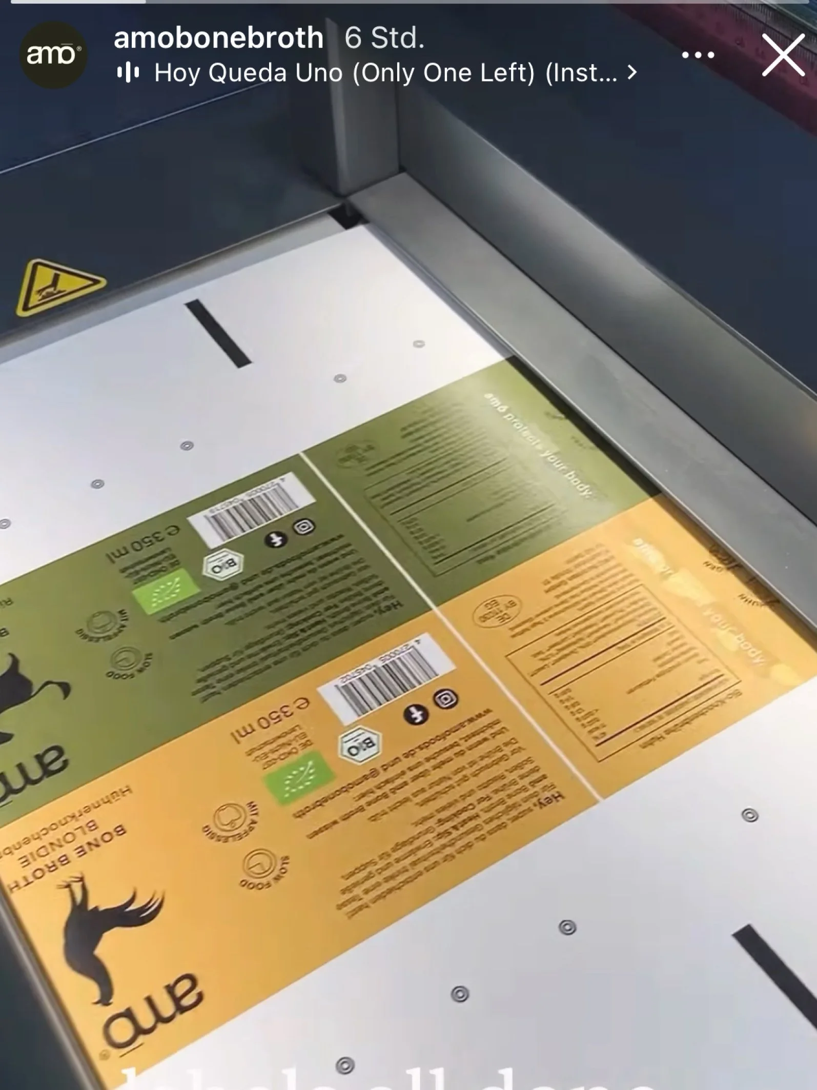 Mehrere Lebensmittelverpackungen in einem Aufzugsfach, darunter ein grüner sowie ein gelber Beutel, mit Text und Barcodes darauf.