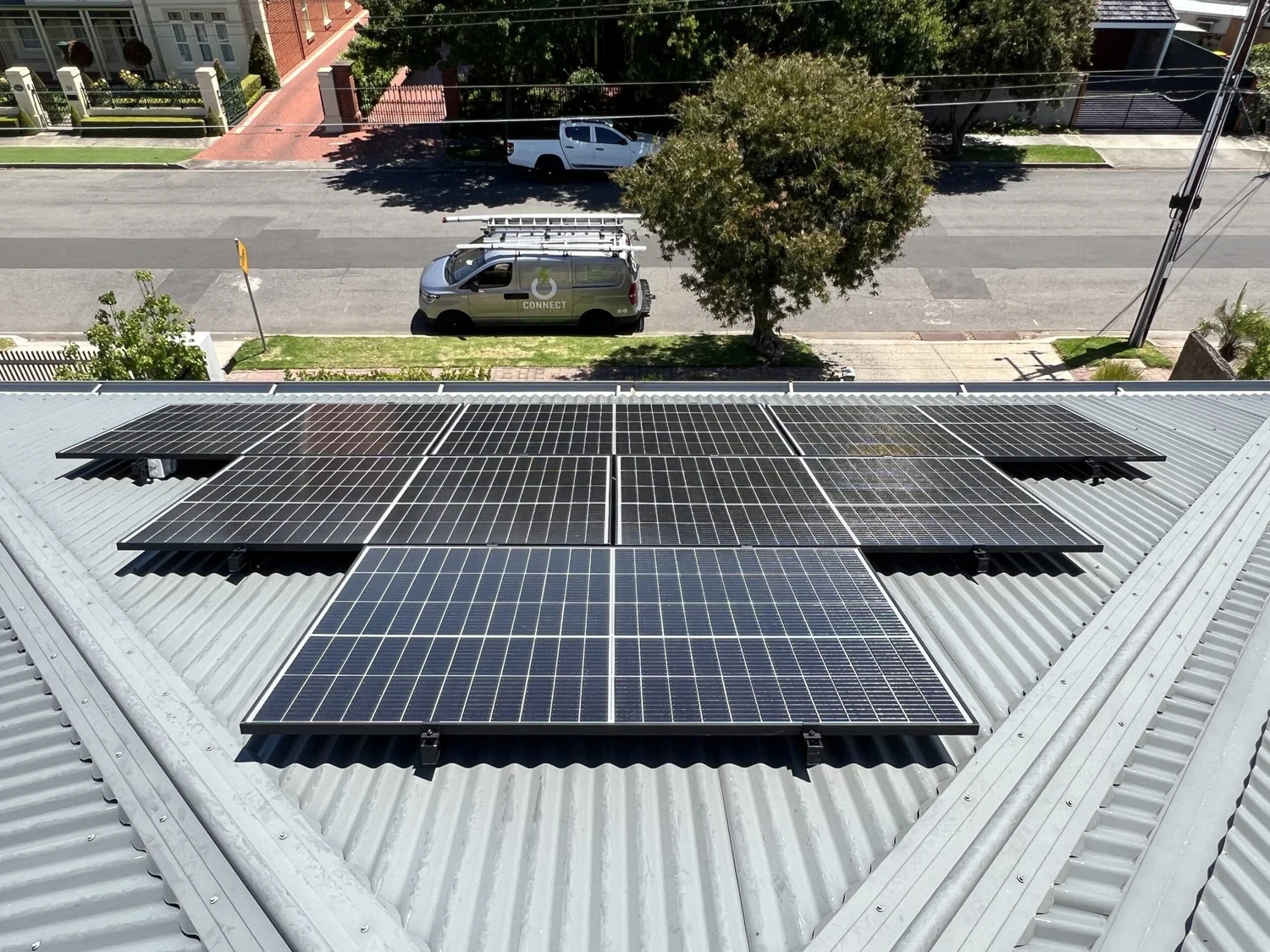Residential rooftop solar panel installation with a Connect Electrical & Solar service vehicle onsite