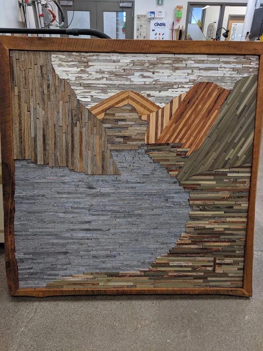 Wood mosaic art depicting a mountain landscape with layered textures and various wood tones.
