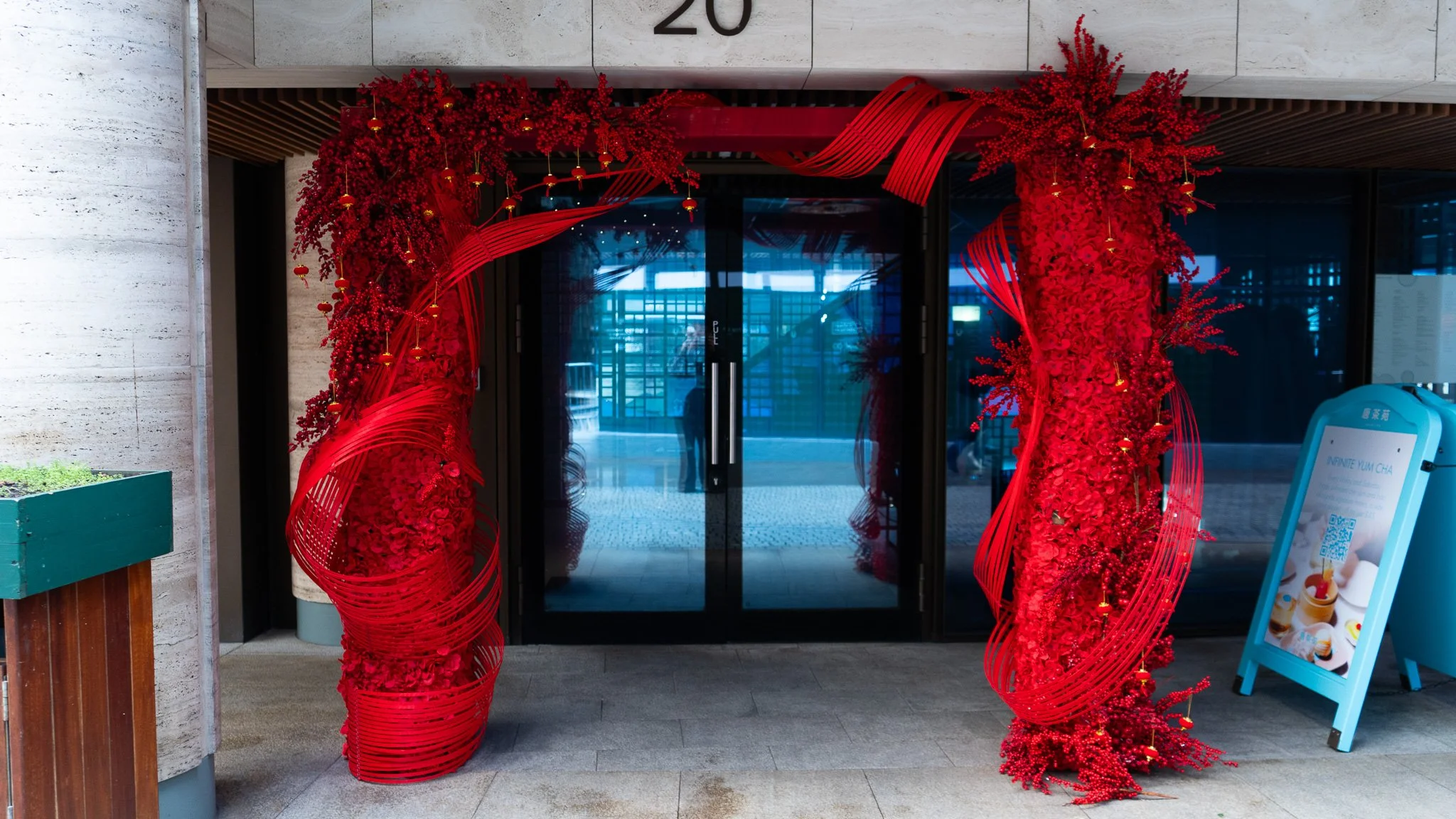 Red floral and ribbon decoration framing glass doors at the entrance of a building.