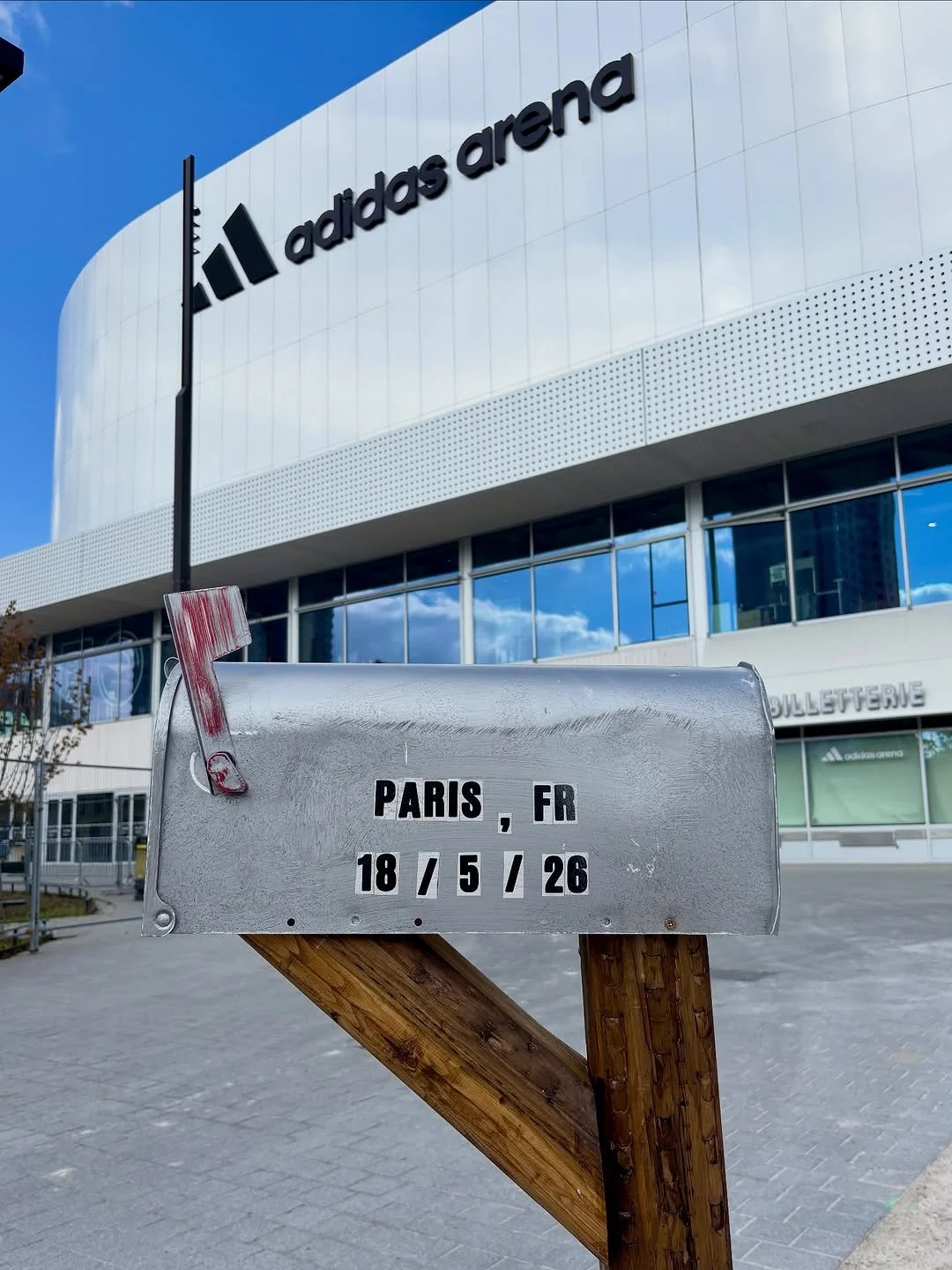 Photo of an Adidas Arena building with a parking sign in the foreground showing the date May 18, 2026, in Paris, France.