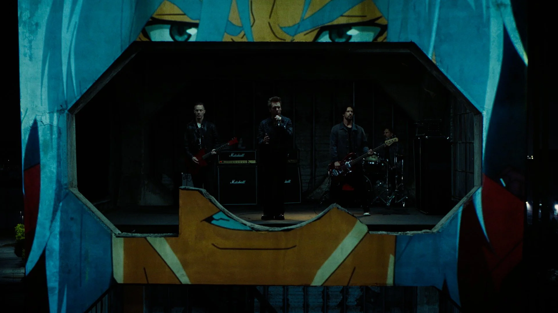 Band performing live on stage with a large tiger face mural above them as seen through a decorative opening.