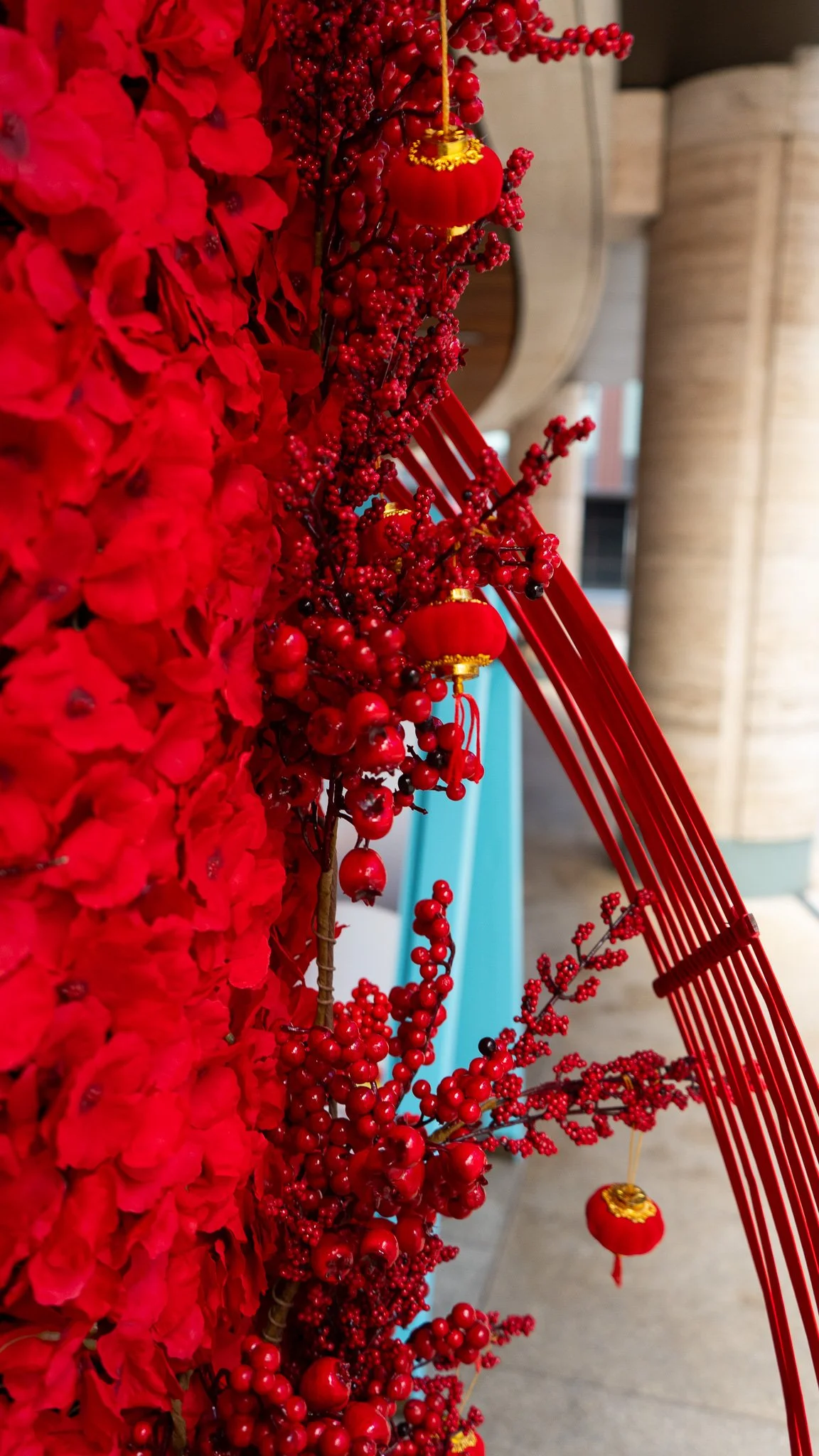 A decorative display featuring red flowers, berries, and ornaments, with red sticks or rods arranged vertically on the right side.