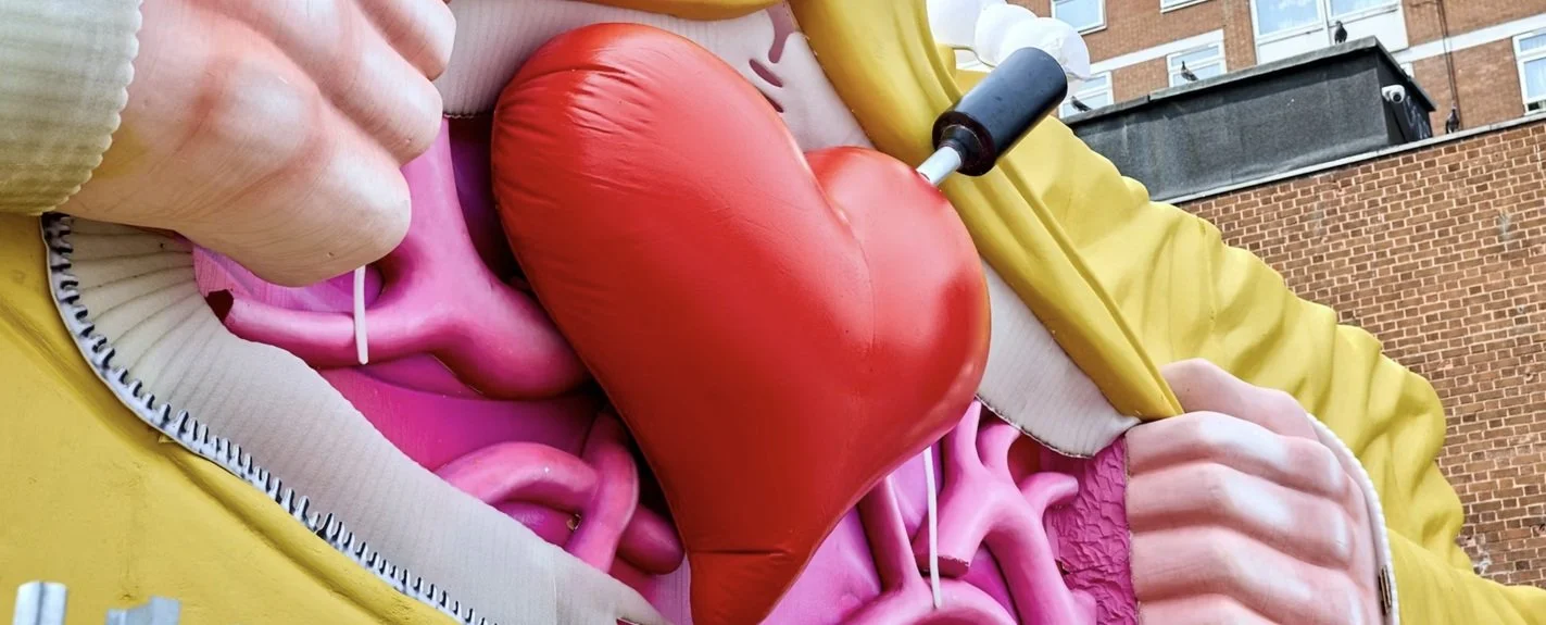 Brightly colored inflatable representation of the human stomach and intestines with a large red heart in the center, displayed outdoors.