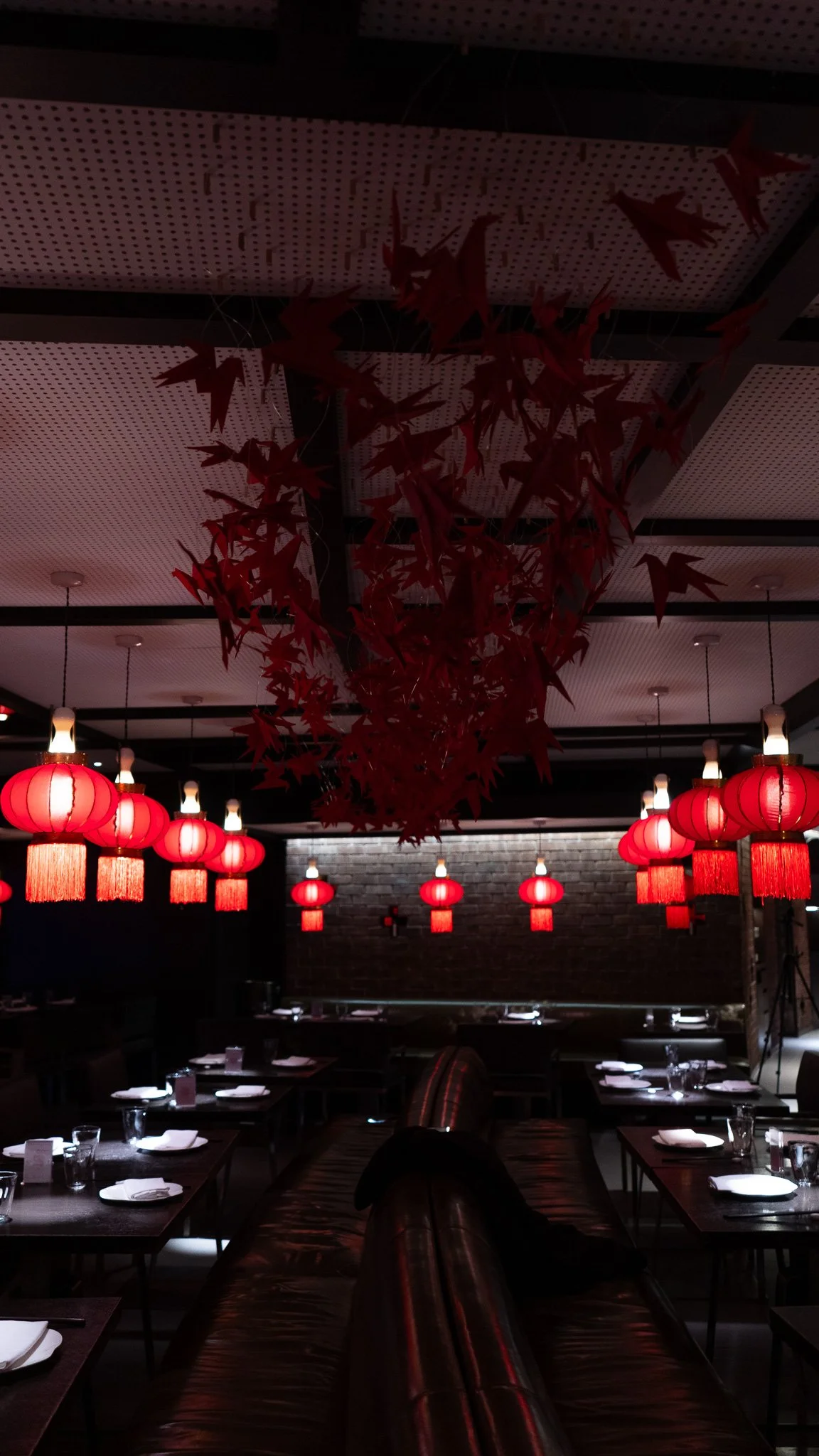 A restaurant decorated with red lanterns and paper autumn leaves hanging from the ceiling.