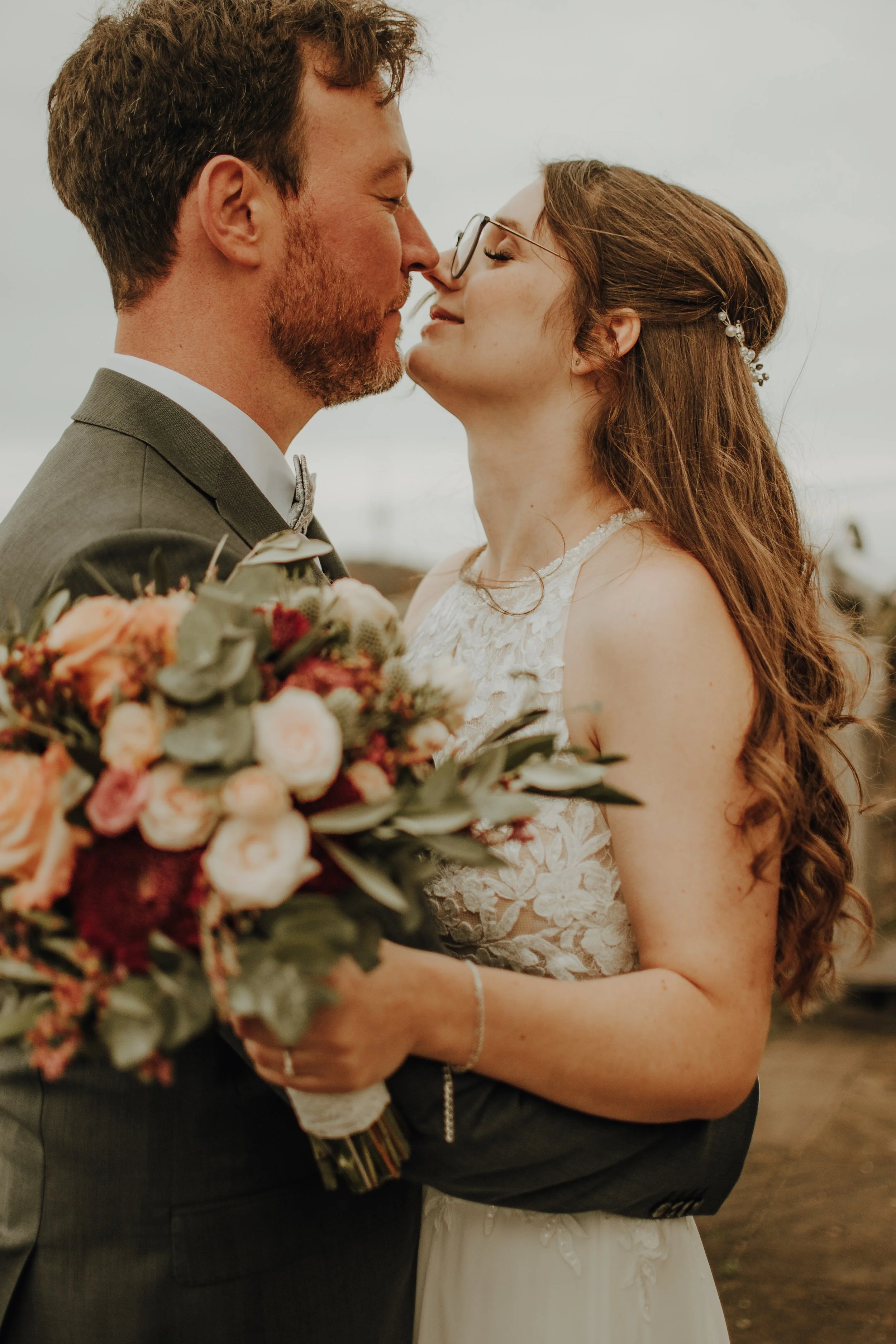 Ein Brautpaar bei einer Hochzeit, das sich mit geschlossenen Augen berührt, während die Braut einen Brautstrauß hält.