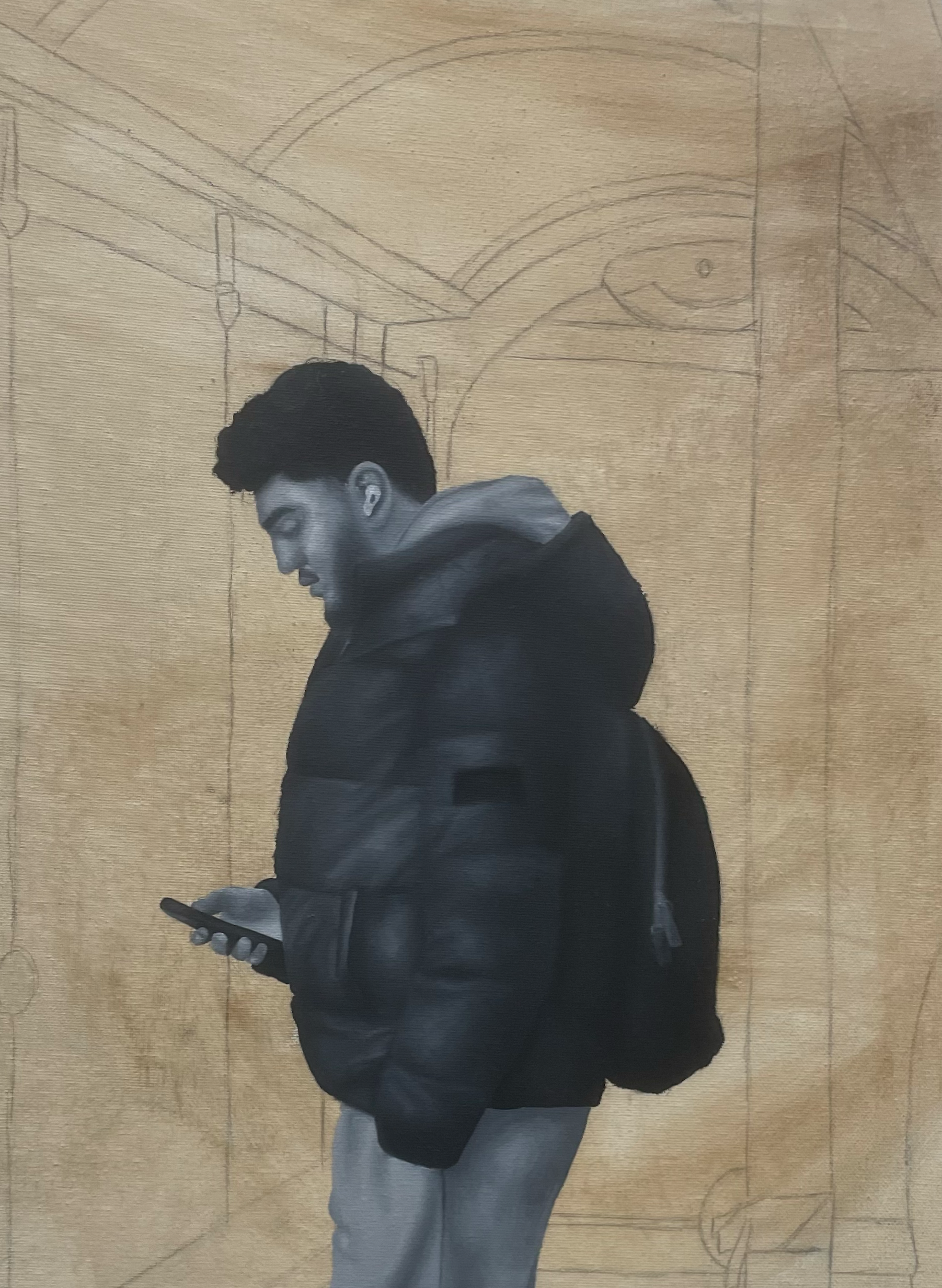A young man with dark hair and a black jacket is looking at his phone while standing in front of a sketch of a motorcycle on a wooden wall.