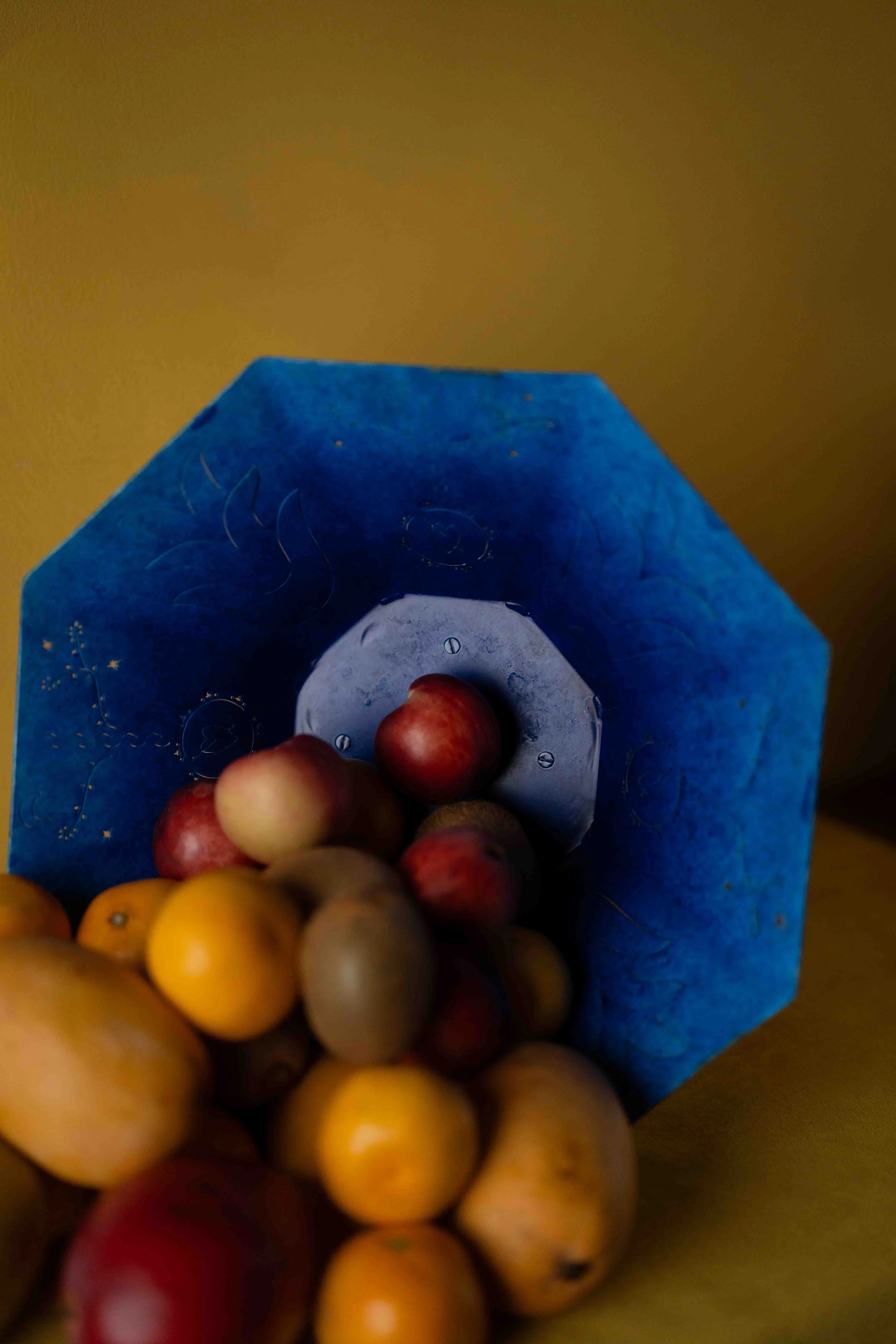 Close-up of a colorful assortment of small round fruits in a blue paper bag, with a blurred background.