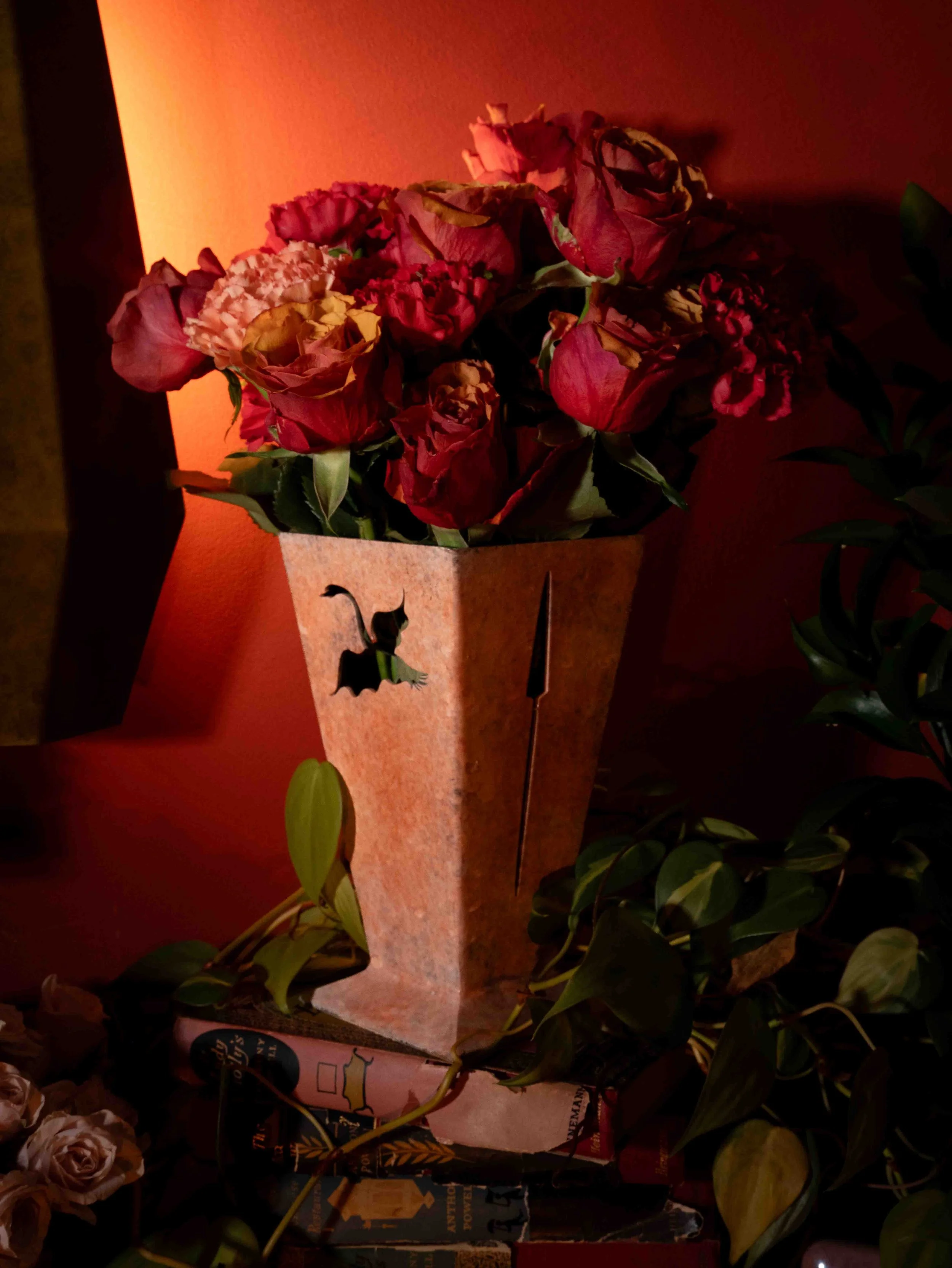 A bouquet of red and pink flowers on a table with a warm orange light background.