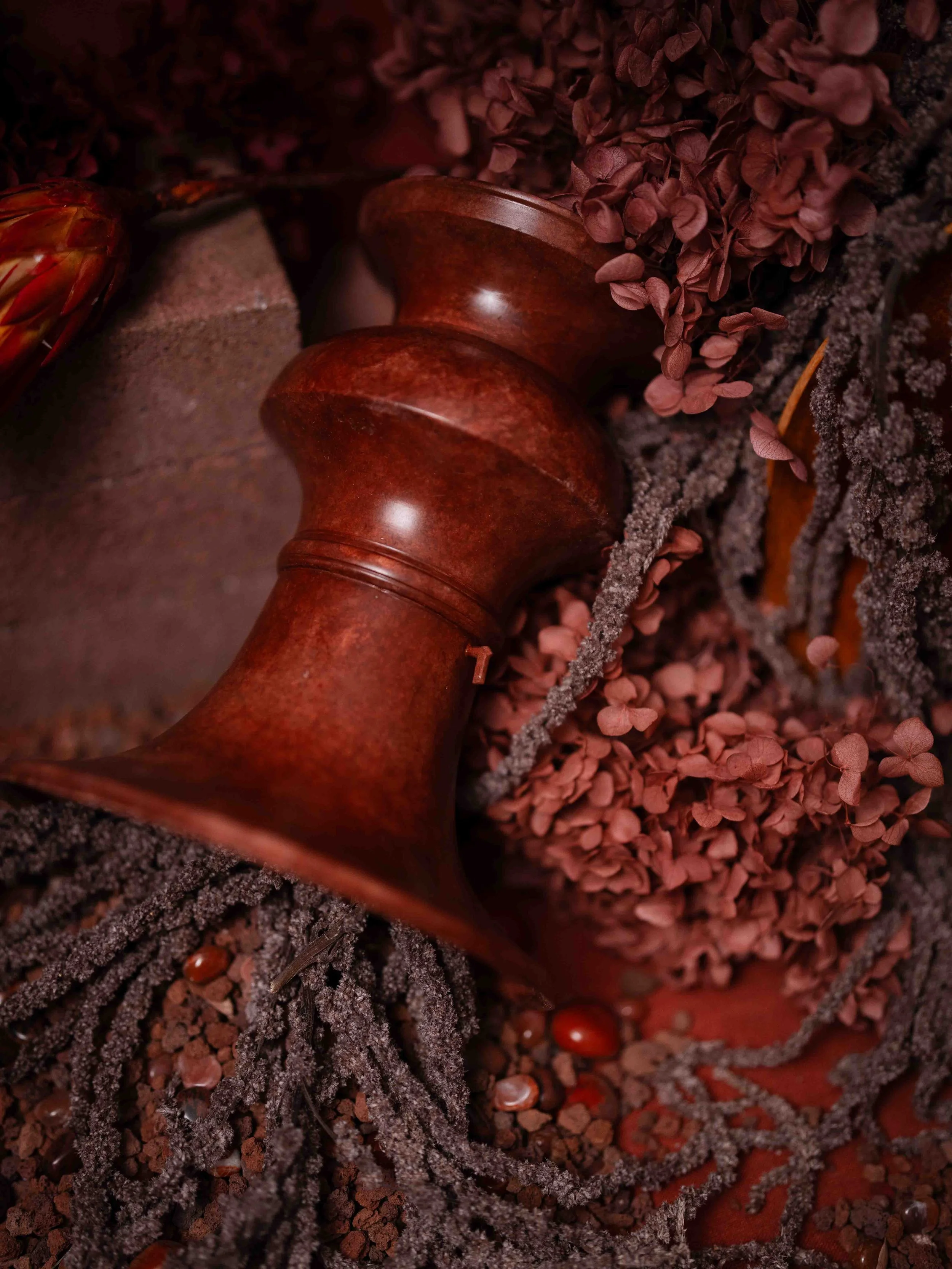 Close-up of a vintage wooden spinning top surrounded by dried flowers, small rocks, and decorative elements with a rustic background.