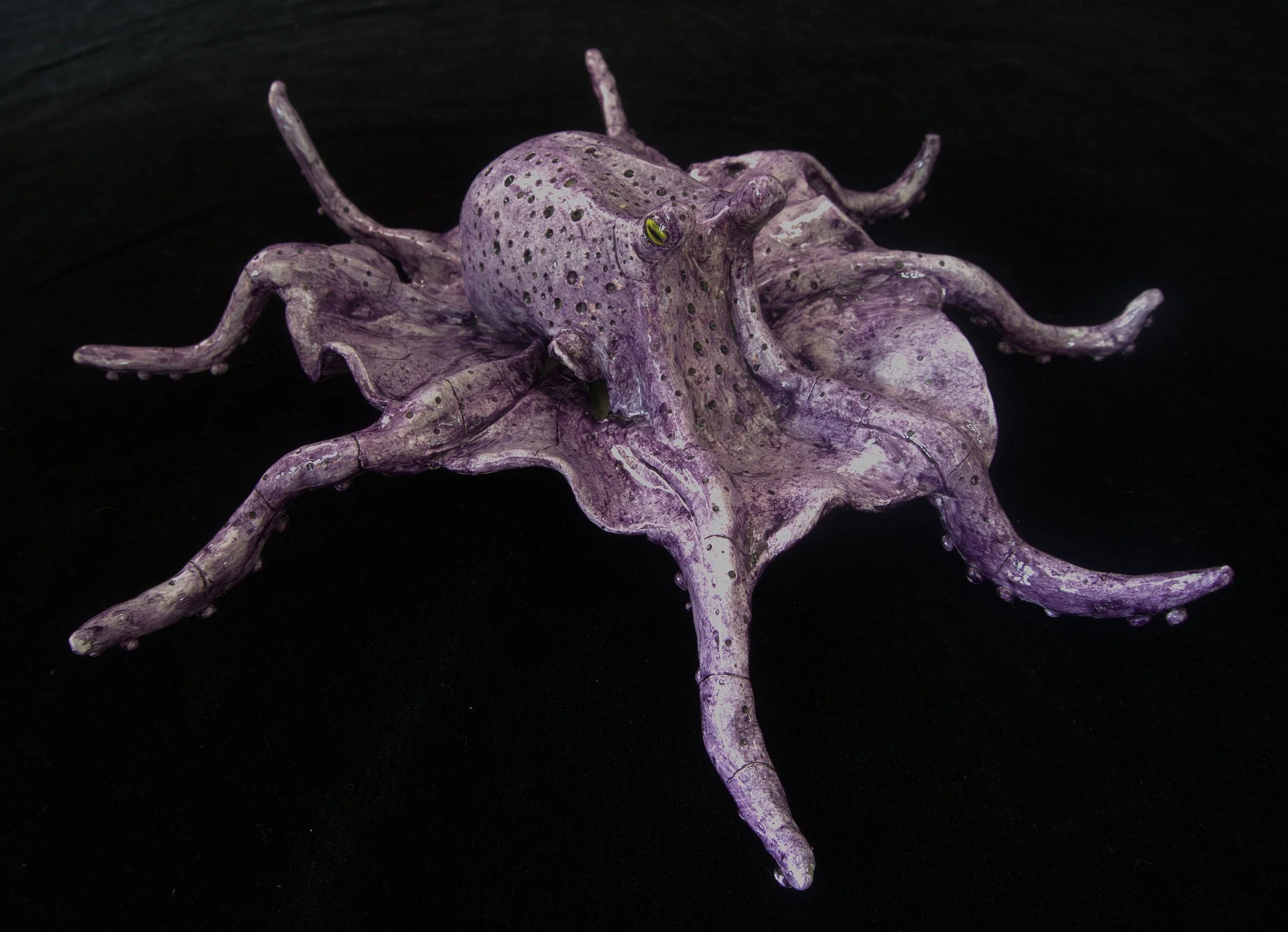 A purple octopus with green eyes and black spots on its body, positioned on a black background.