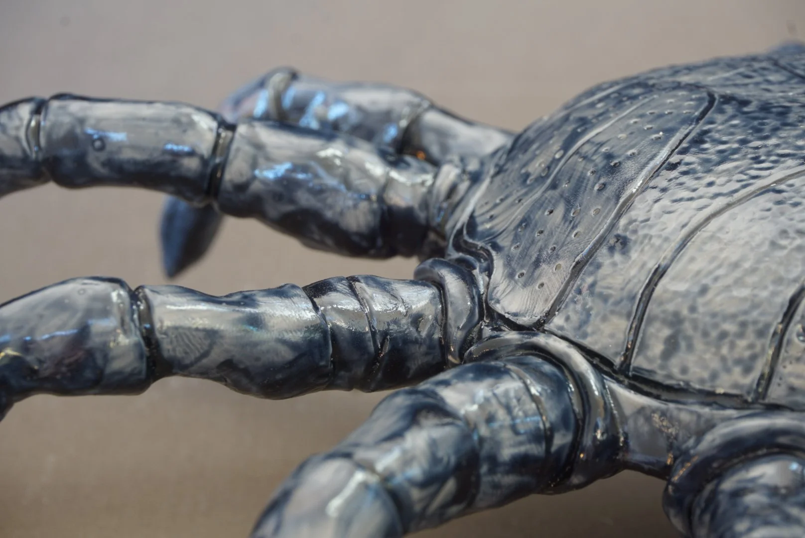 Close-up of a metallic sculpture resembling a robotic or stylized human hand with detailed fingers and textured surface.