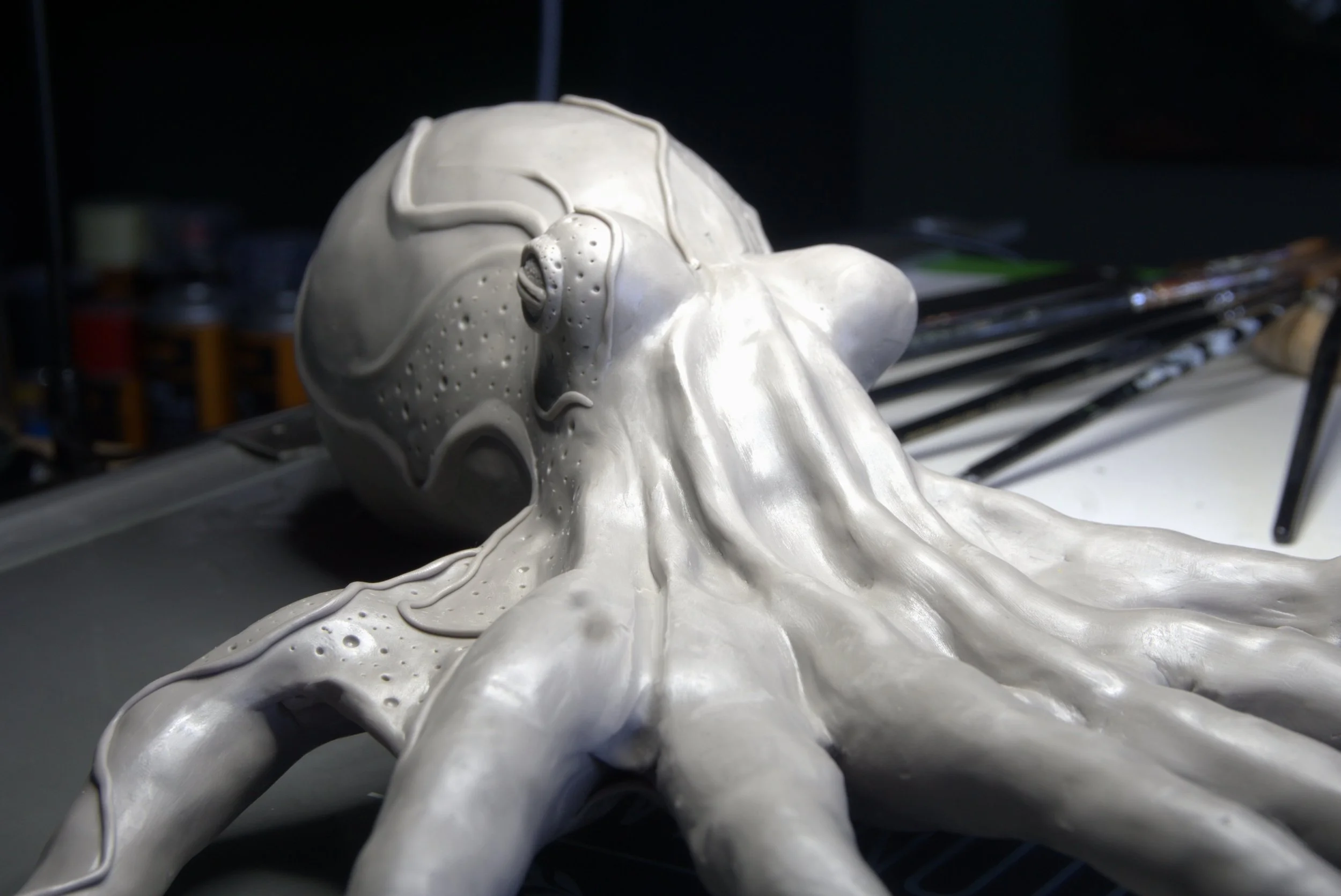 A sculpture of a reclining figure with intricate patterns and flowing shapes, made of a shiny, silver material, resting on a flat surface.