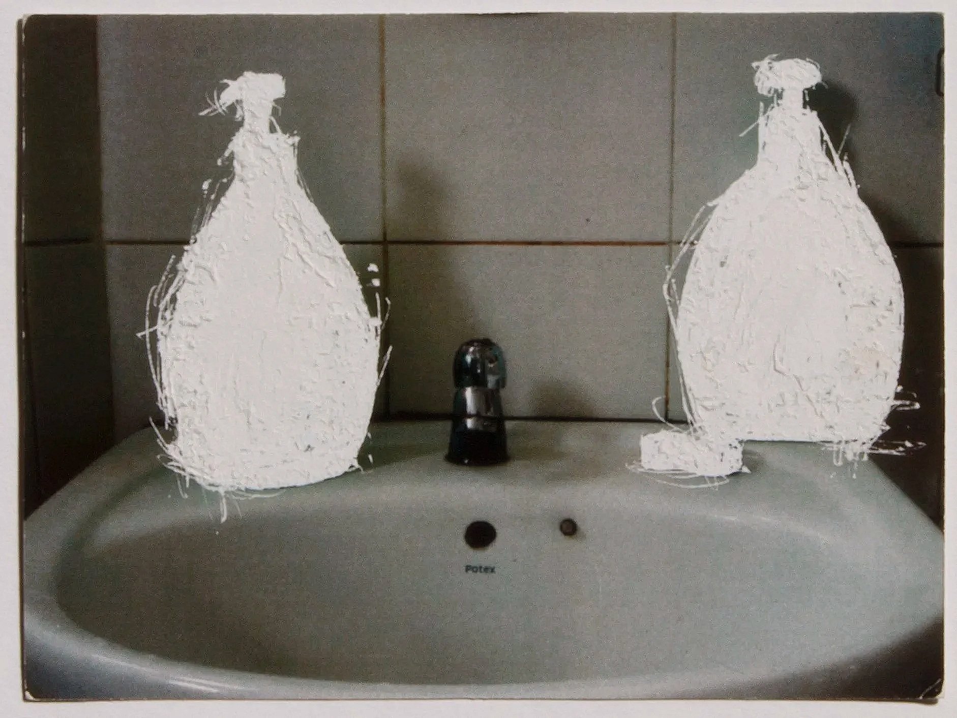 Somber yet expressive image of a washbasin in shadow, with soap dispenser bottles physically etched out of the picture surface.
