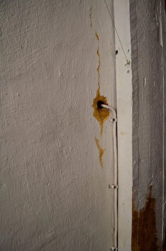 Gold enamel painted into nooks and crannies of a white plastered wall to resemble leaking gold.