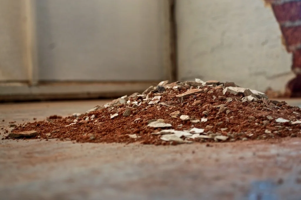 Pile of crumbled and disintegrated red brick on the floor as part of a site-specific art installation. 