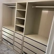 Empty beige open closet with shelves and drawers