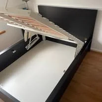 Disassembled bed frame with mattress support removed, showing the bed's structure.