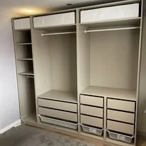Empty built-in closet with shelves and drawers on a light-colored wall.
