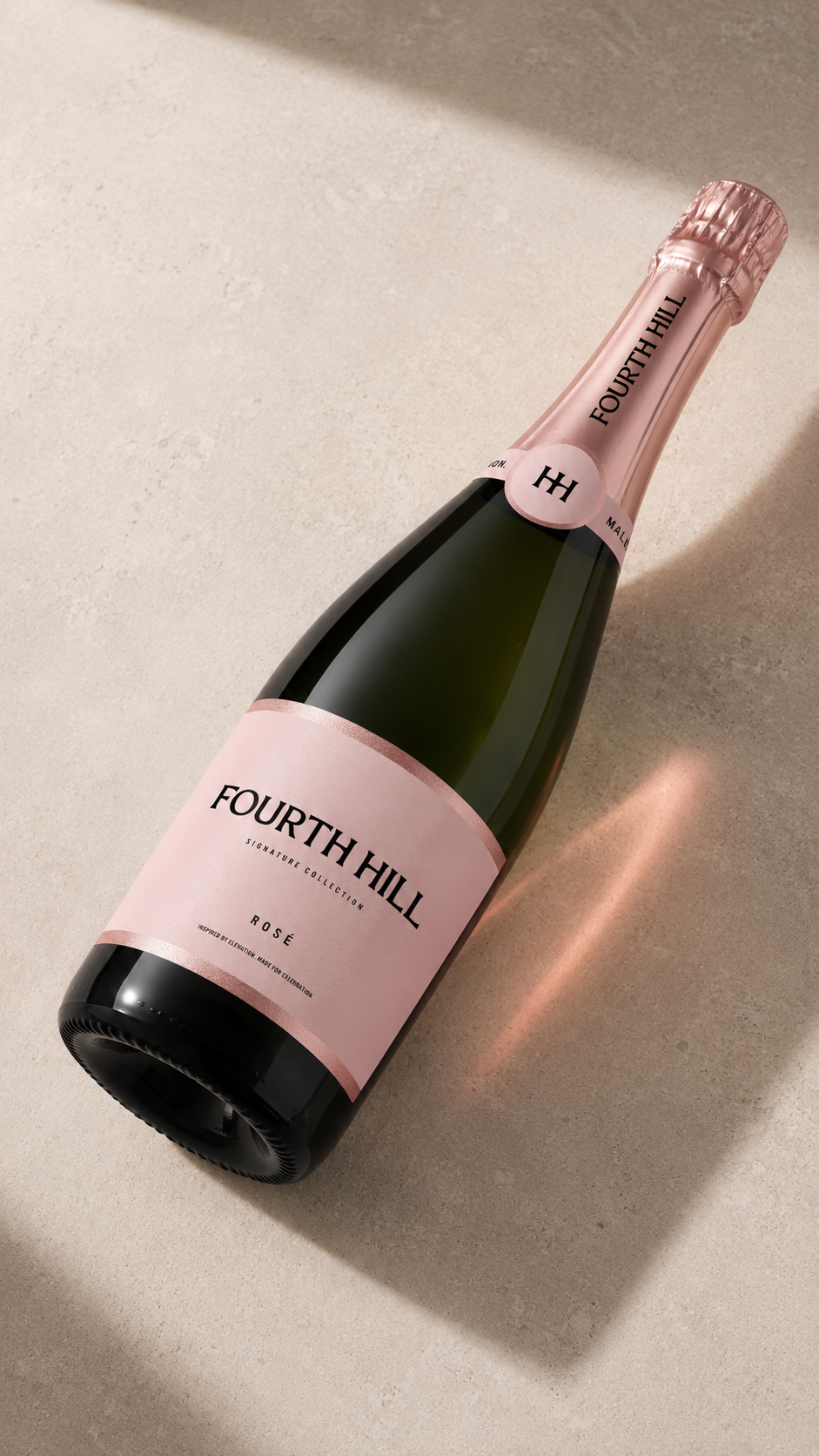 A bottle of Fourth Hill Rosé sparkling wine lying on a beige surface with soft shadows.