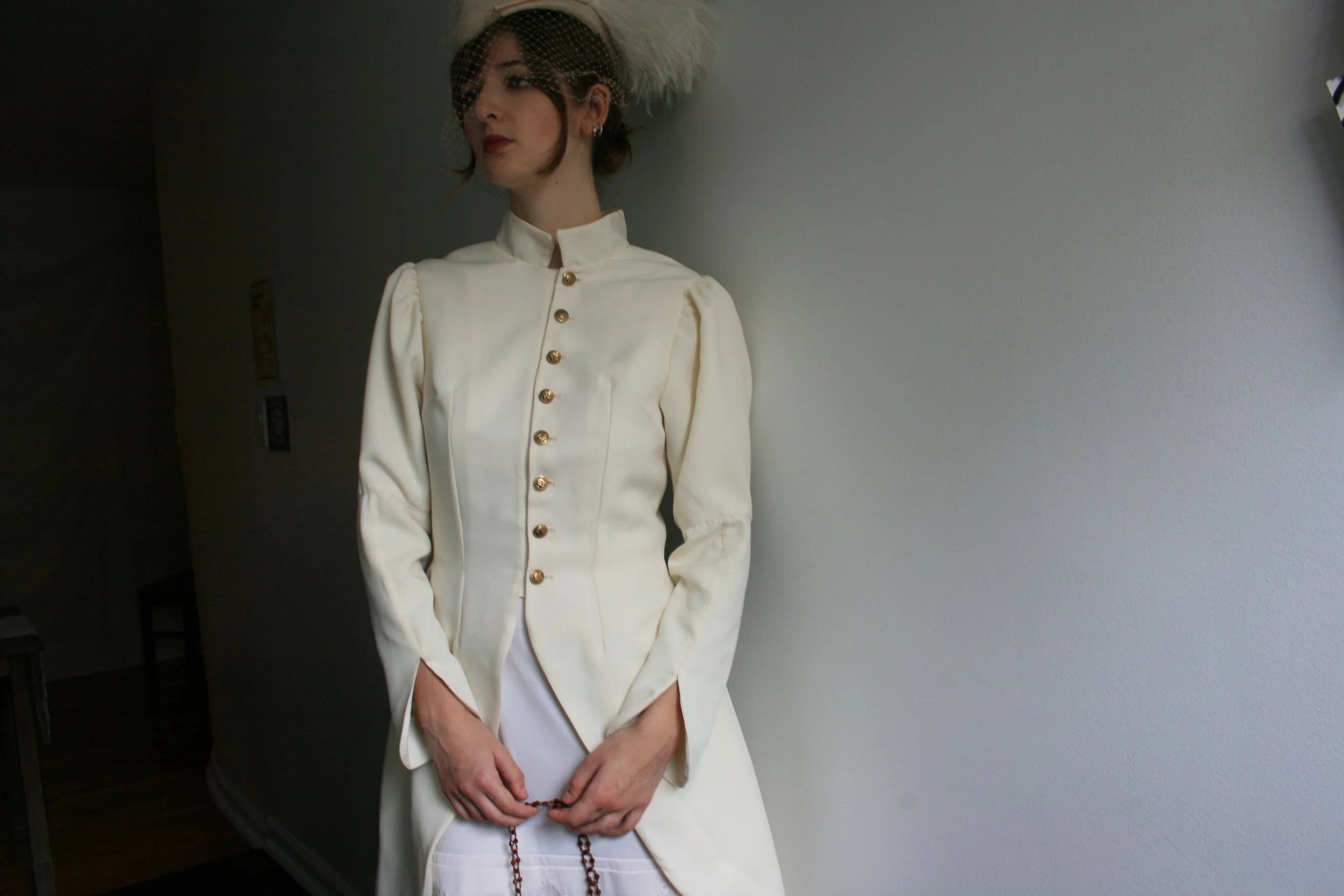 wool gaberdine coat with gathered 3 piece sleeves, standing collar, and gold shank buttons 