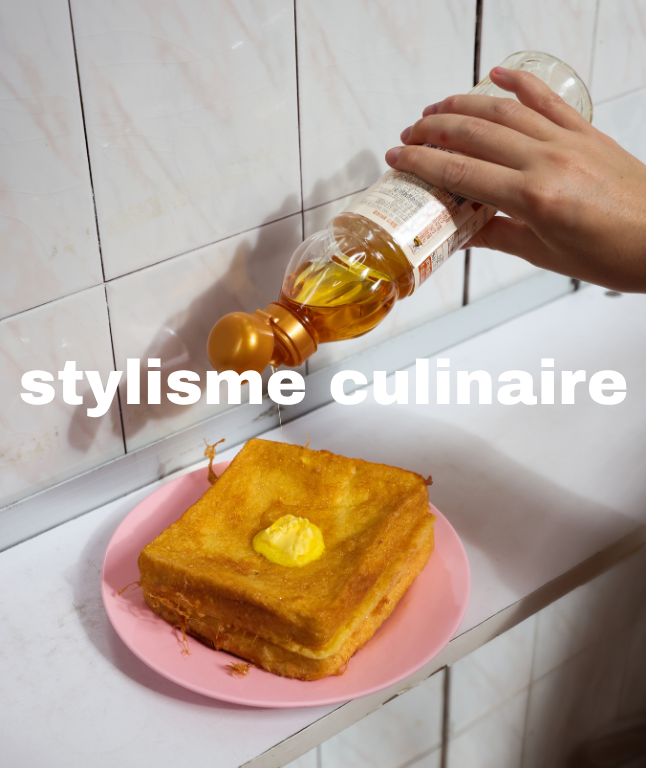 Une main verse de l'huile dans une assiette avec un morceau de pain de mie grillé posé dessus, sur le comptoir d'une cuisine avec du carrelage blanc