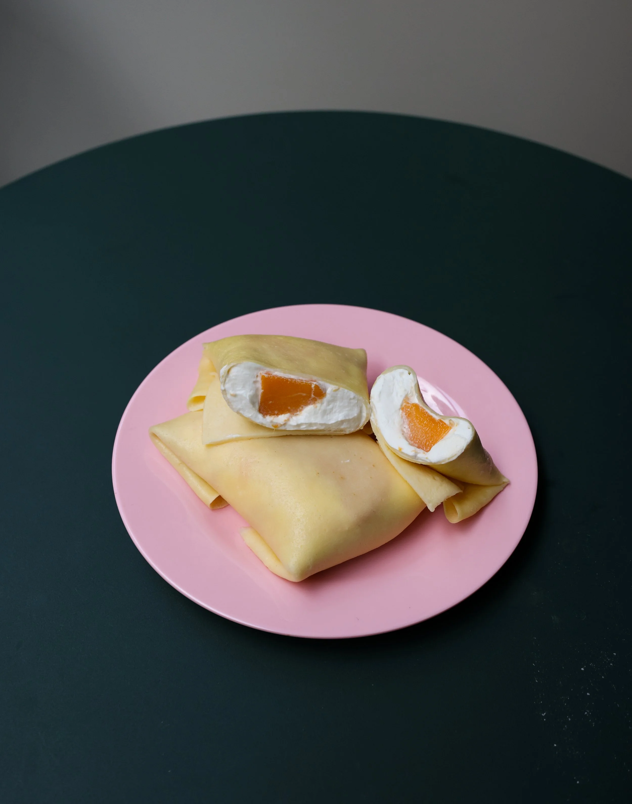 Gâteau roulé à la vanille avec des morceaux de fruits et de la crème sur une assiette roses