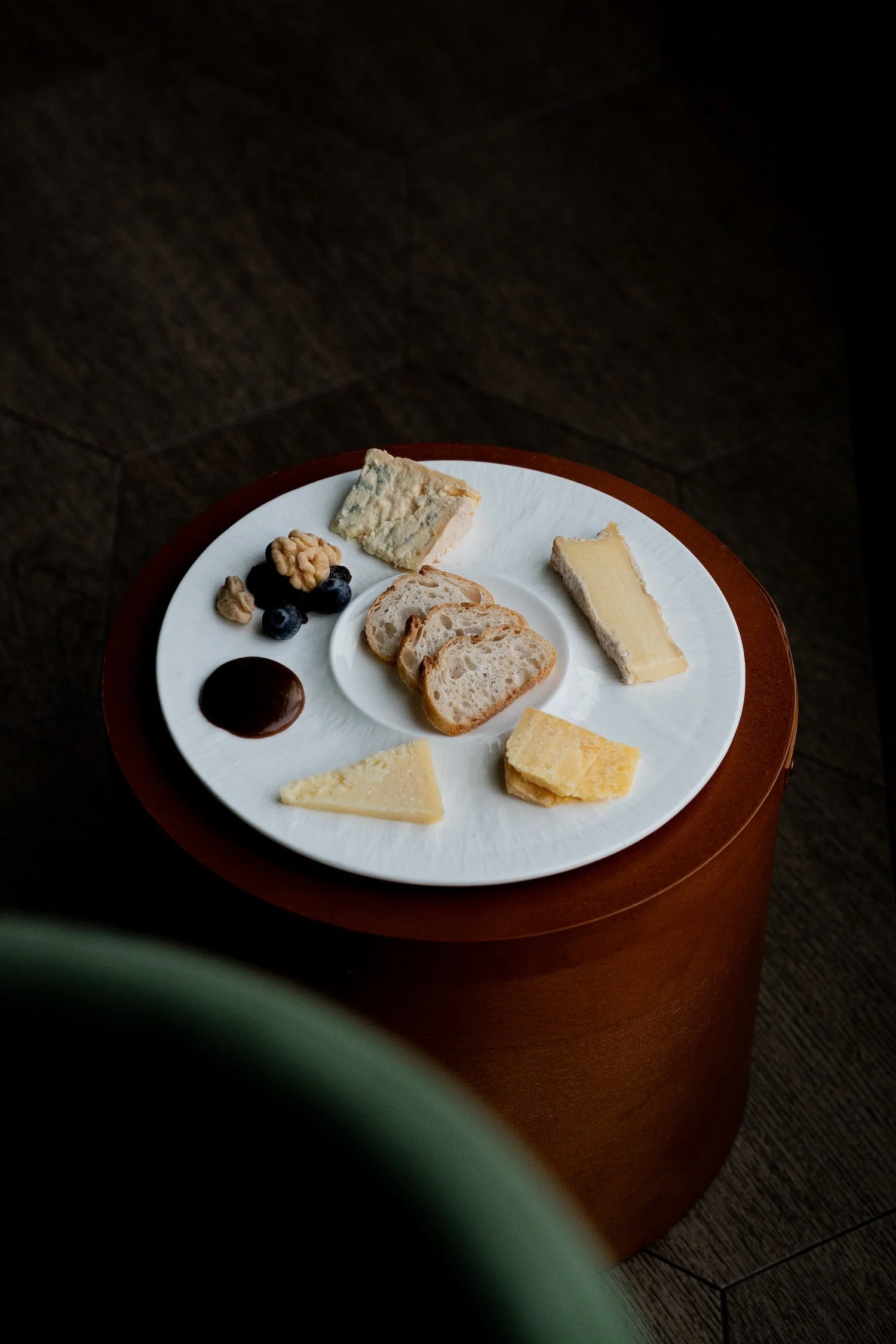 Plate de fromages avec pain, fruits, noix, confiture, et divers types de fromage.