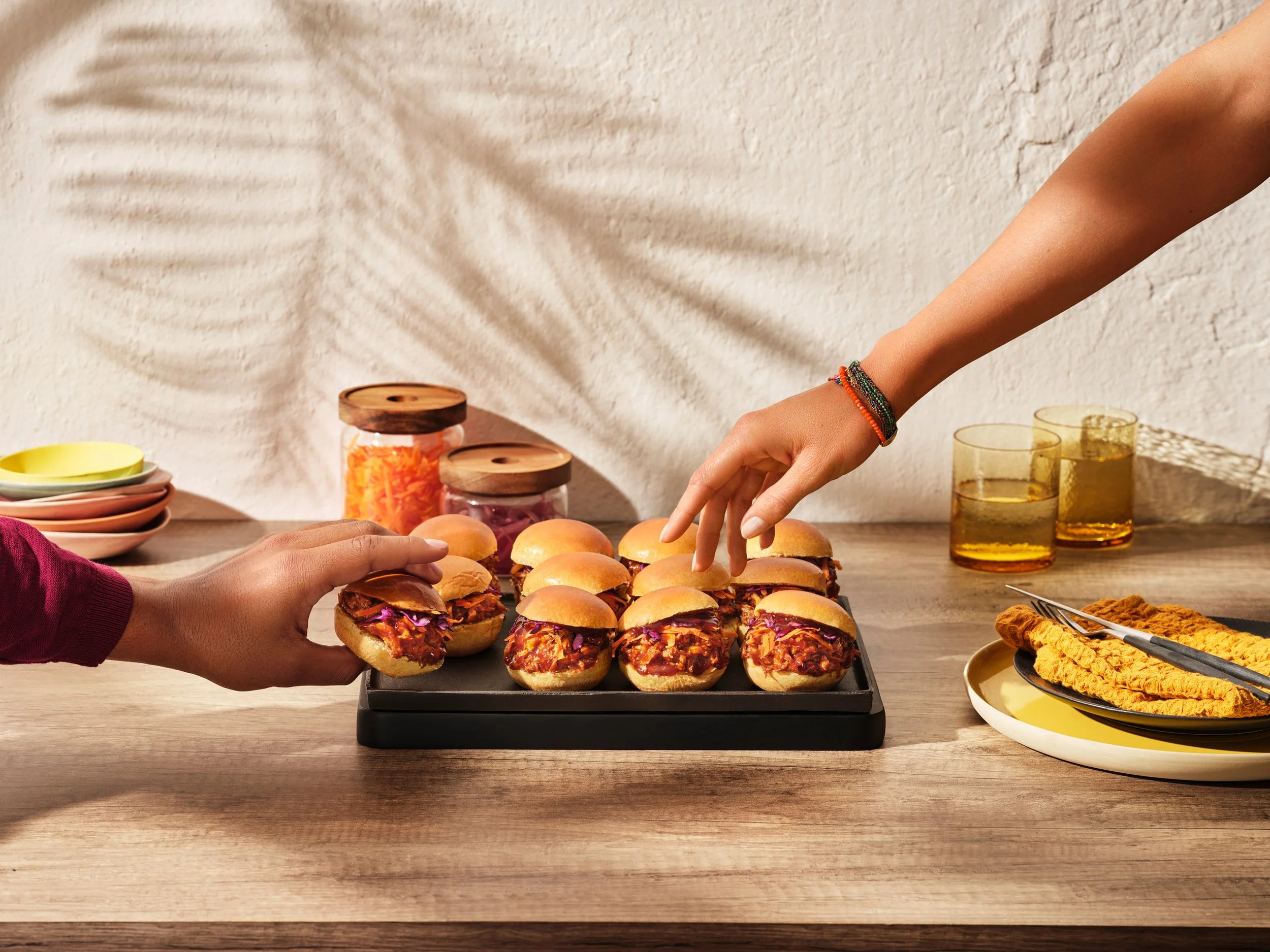 Groupe de sandwiches avec de la sauce à l'intérieur, situés sur une plaque noire sur une table en bois.